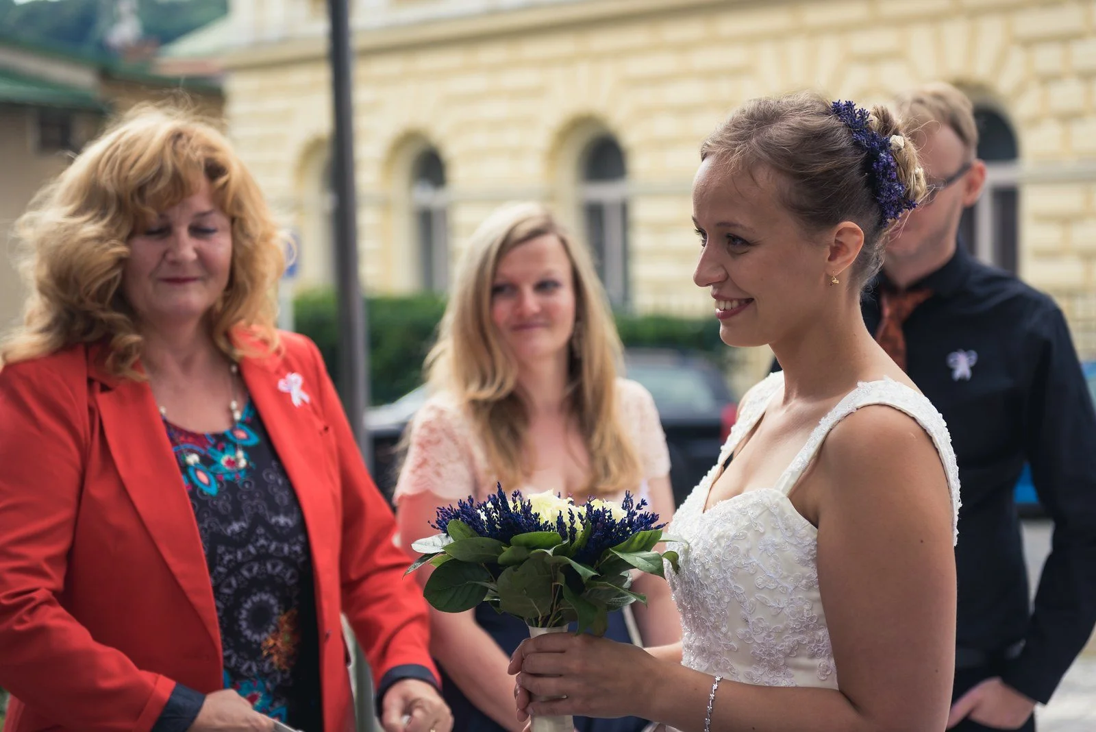 Nevěsta s kyticí hovoří se dvěma ženami před obřadem.