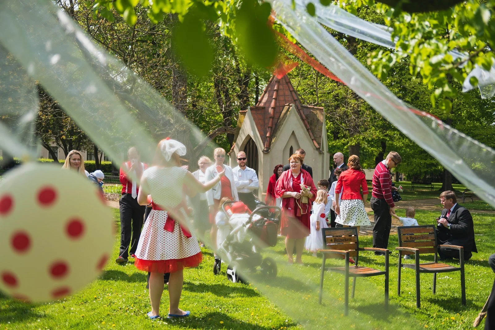 Dvě zavěšené hrací kostky rámují skupinu lidí na trávníku.