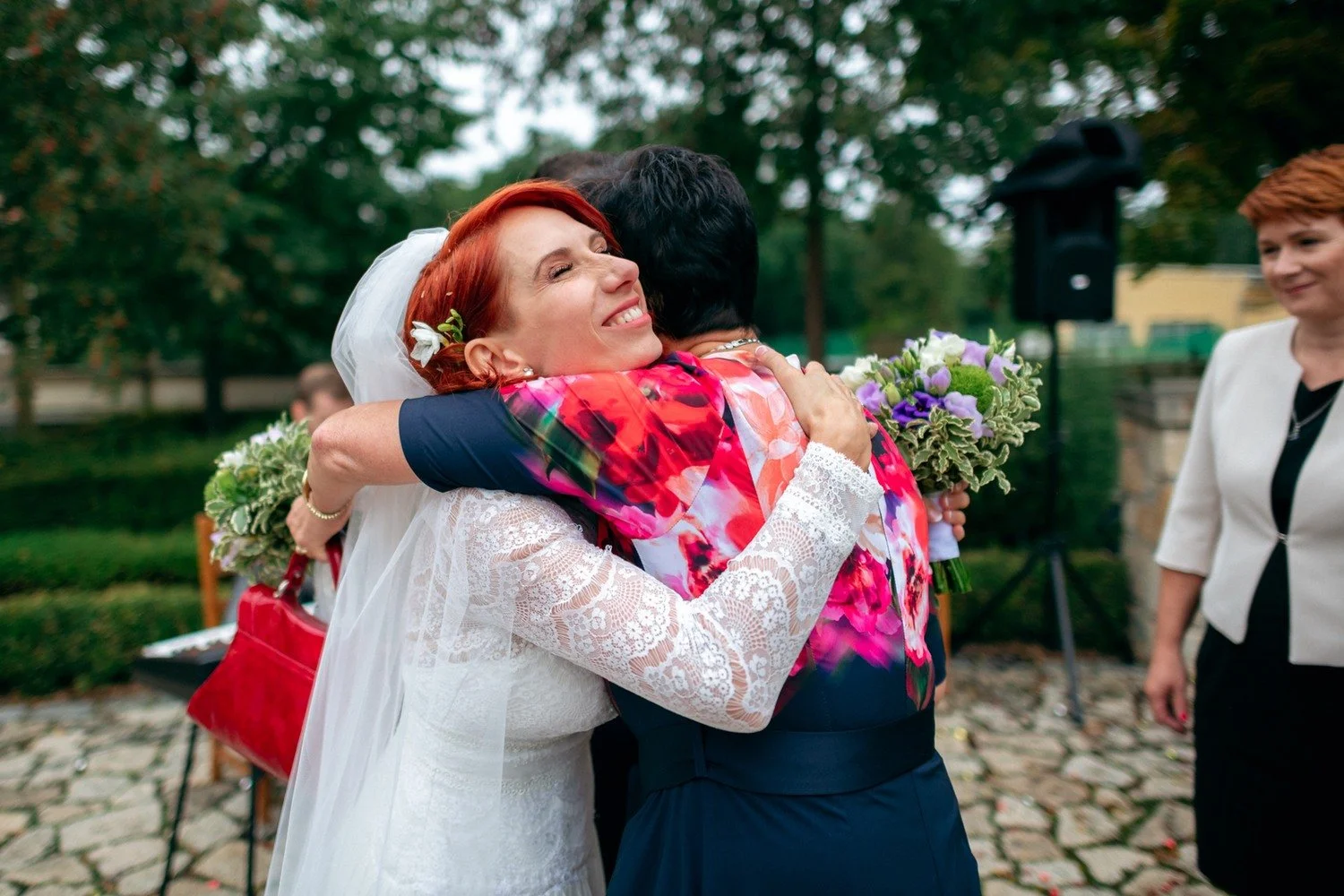 Martina objímá usměvavou ženu v pestrých květovaných šatech.