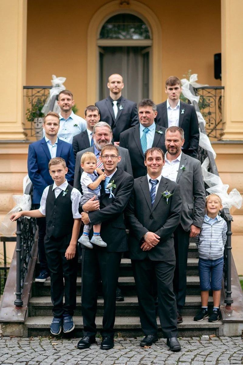 Skupina mužů a chlapců pózuje na schodišti Galerie Villa Pellé.
