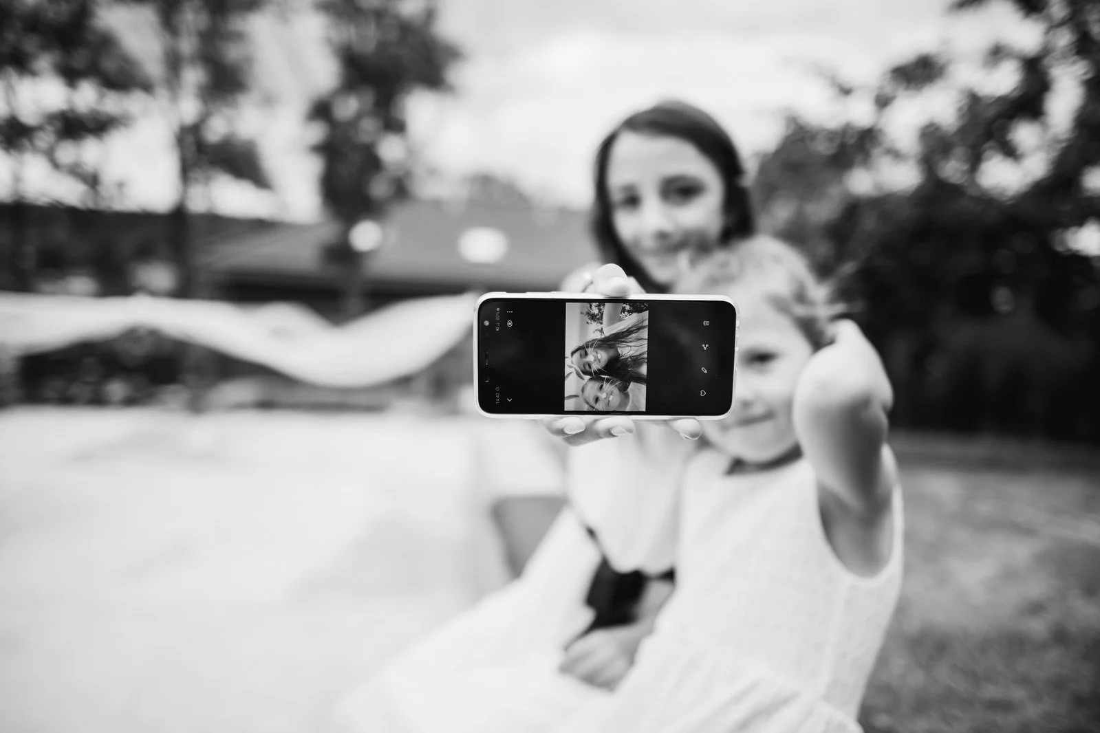 Černobílý snímek ženy fotografující telefonem přidává pozorovaný moment.