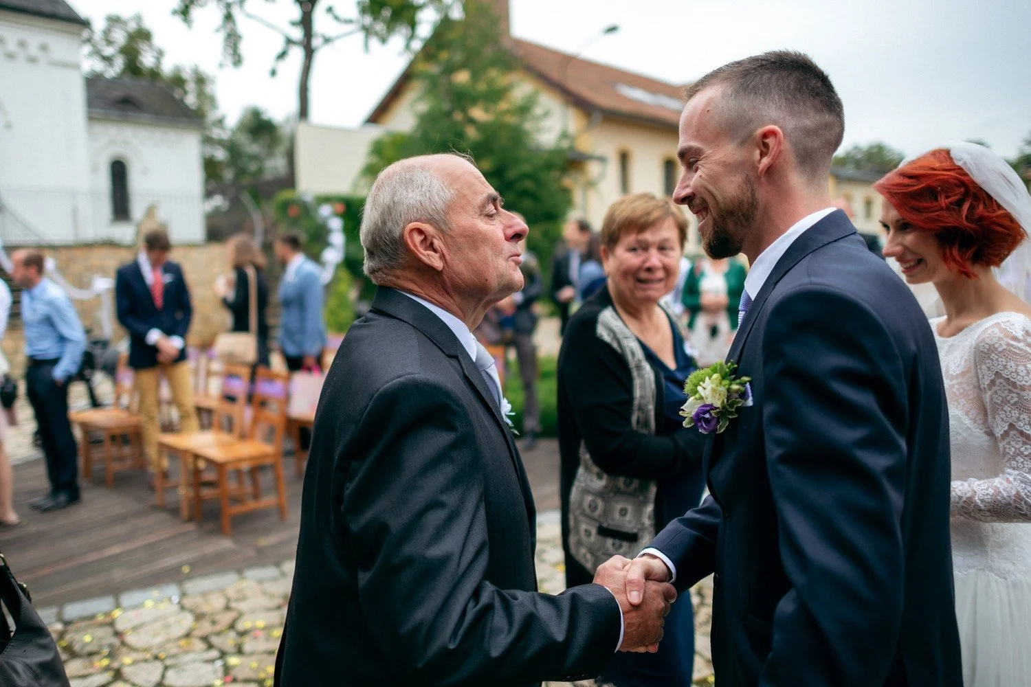 Dva muži si podávají ruce během gratulací na nádvoří.