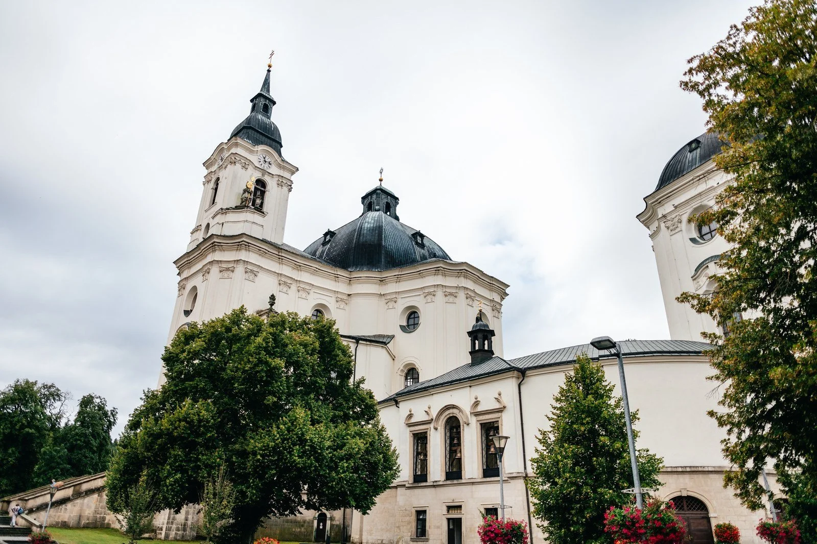 Široký pohled na barokní kostel ve Křtinách pod modrou oblohou.
