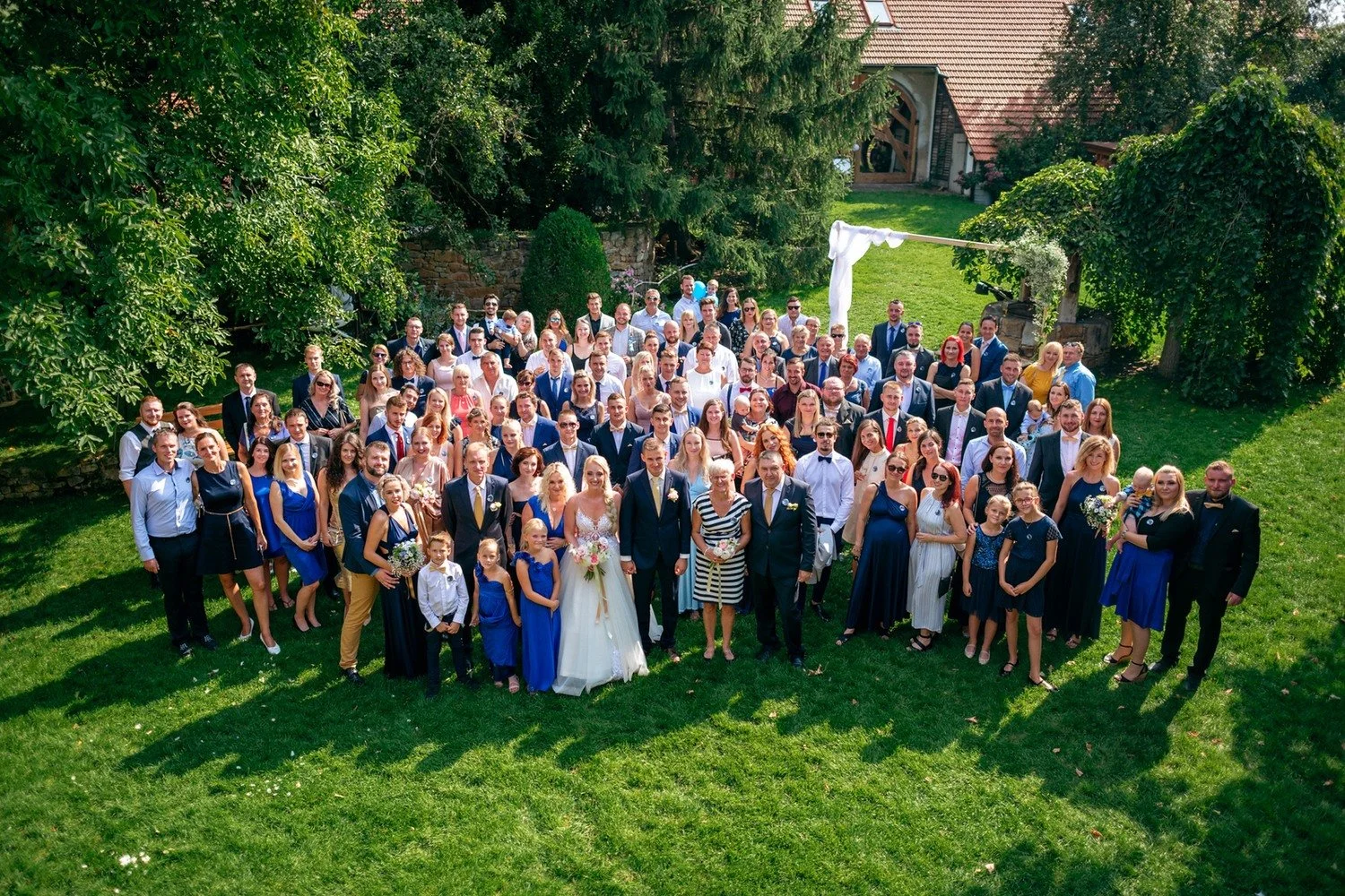Velká společná fotografie všech hostů v zahradě statku