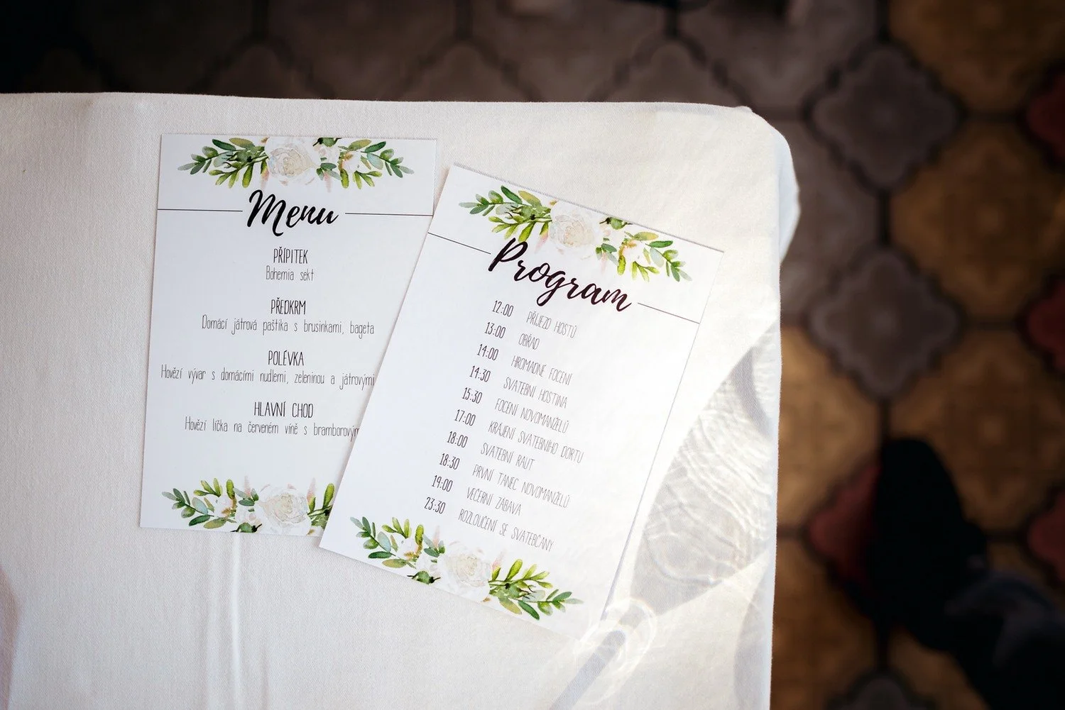 Kartičky s nápisy Menu a Program zdobené jemnými zelenými větvičkami.