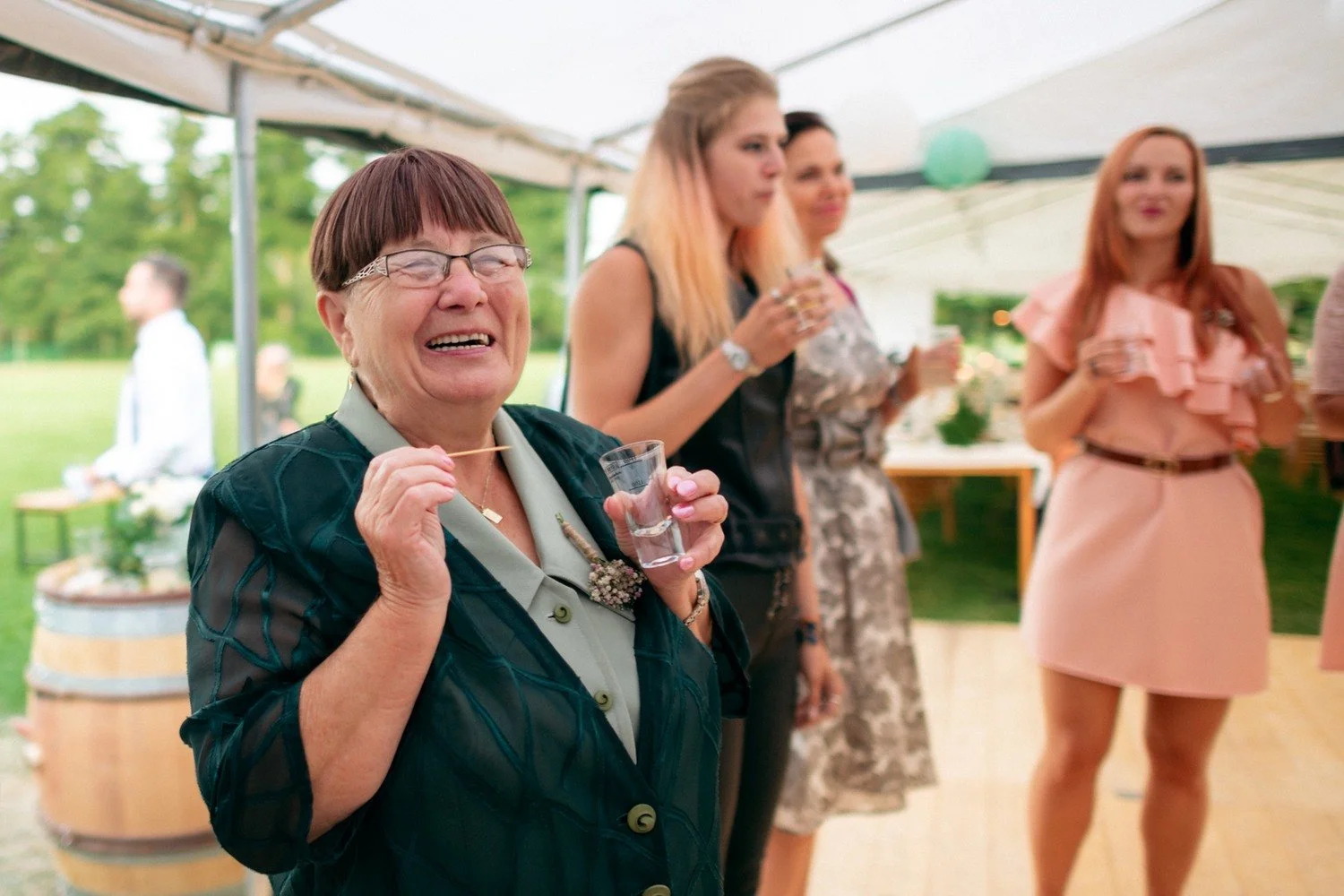 Žena s brýlemi se při tanci široce směje a drží ruce před sebou.