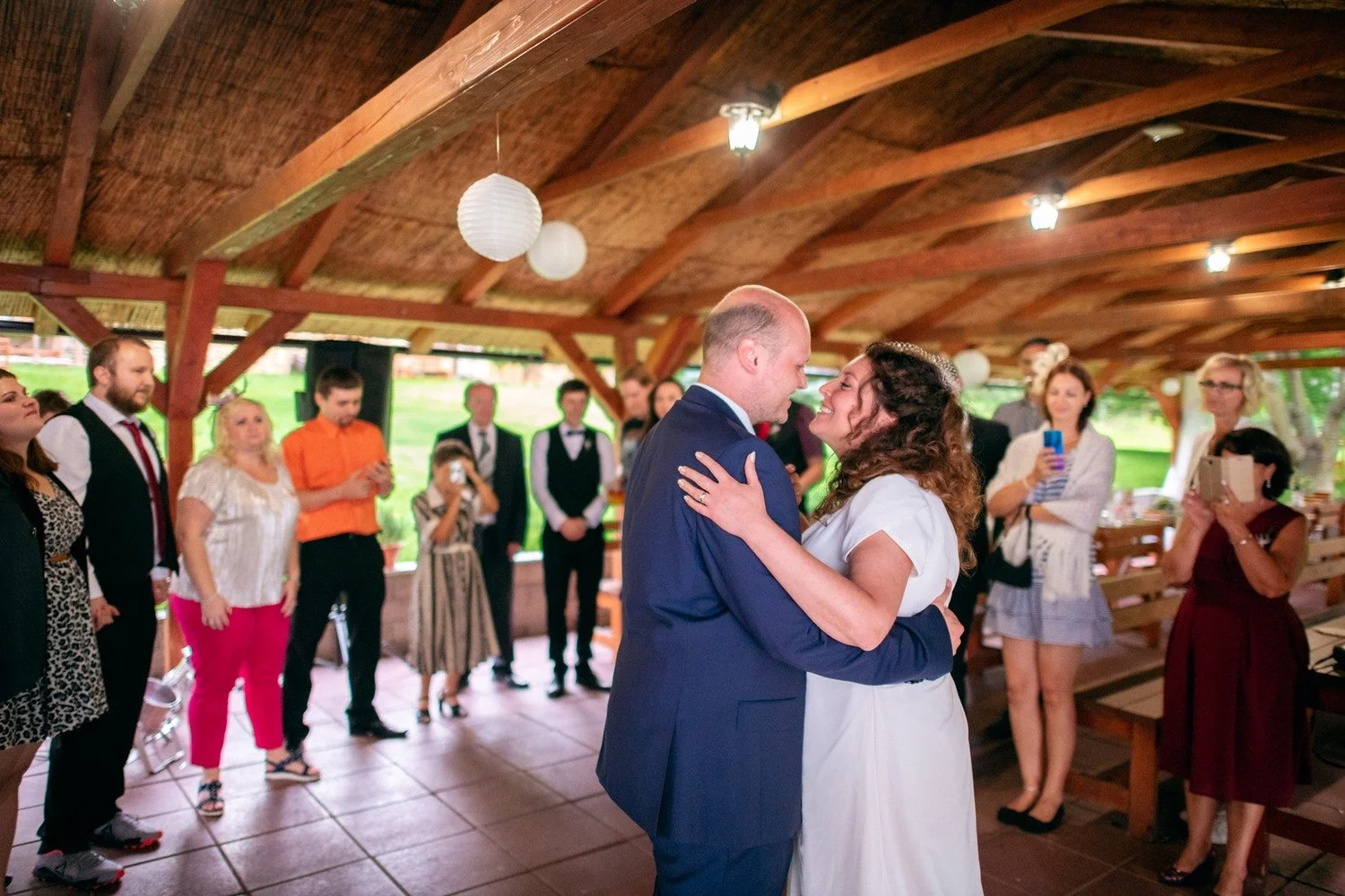 Nevěsta a ženich tančí uprostřed kruhu hostů.