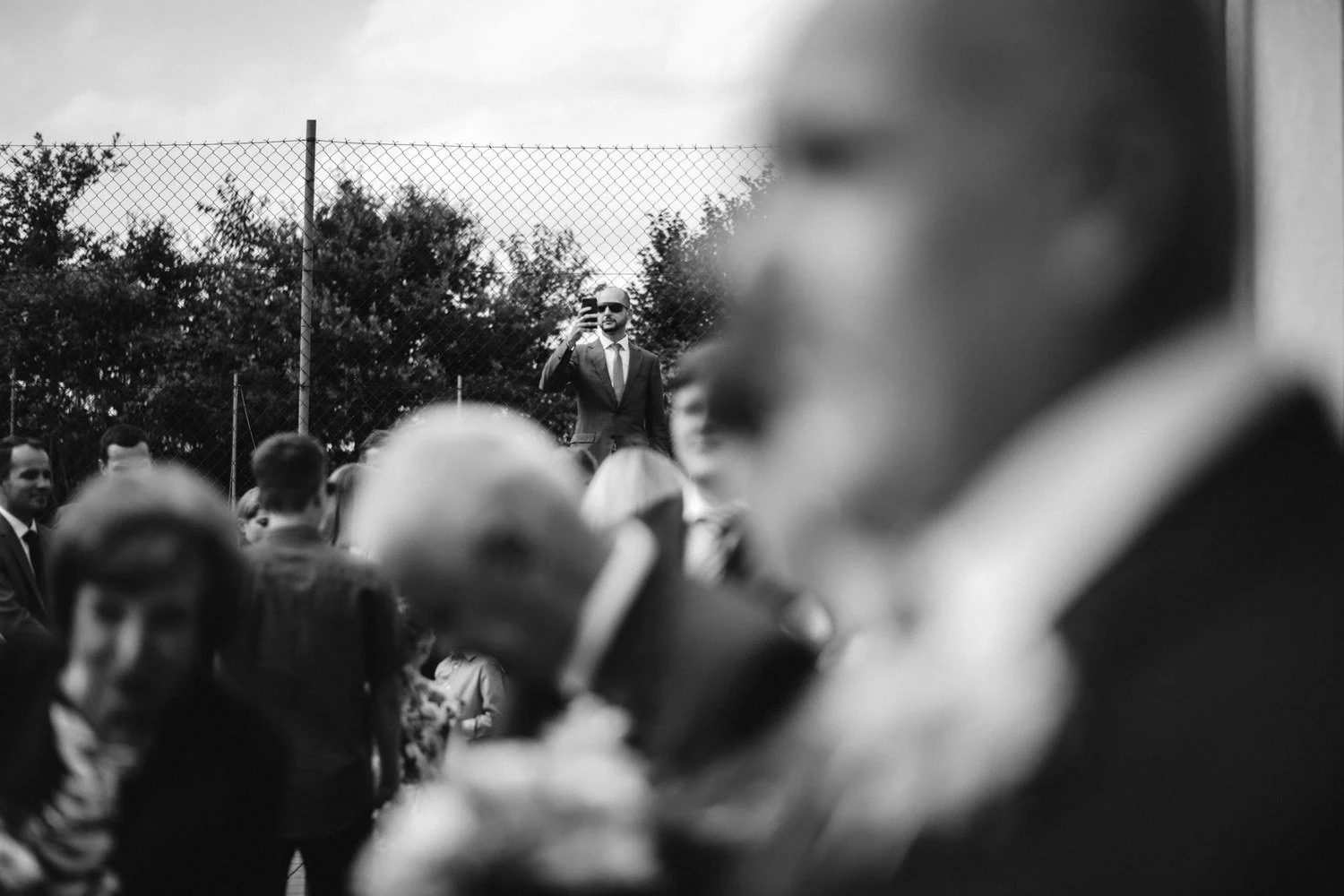Černobílý detail gratulací s hosty zachycenými v mělké hloubce ostrosti.