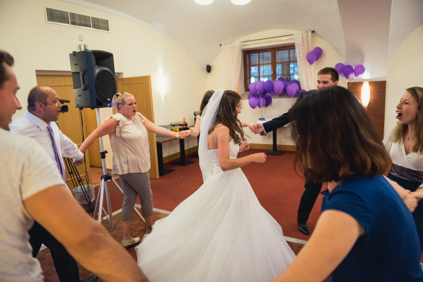 Roztočená světlá sukně vytváří výrazný kruhový pohyb mezi tančícími lidmi.