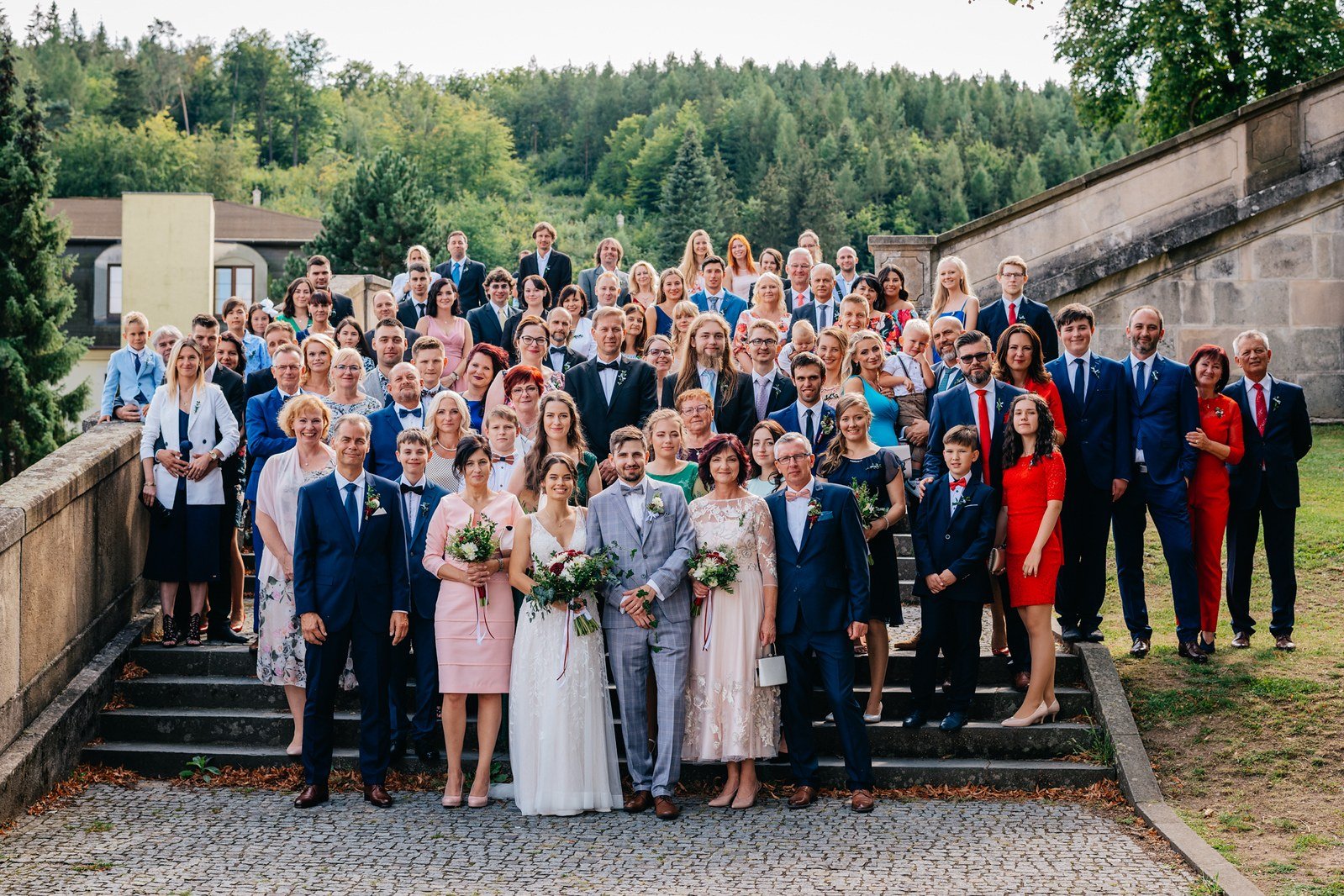 Velká skupinová fotografie na schodech před kostelem.