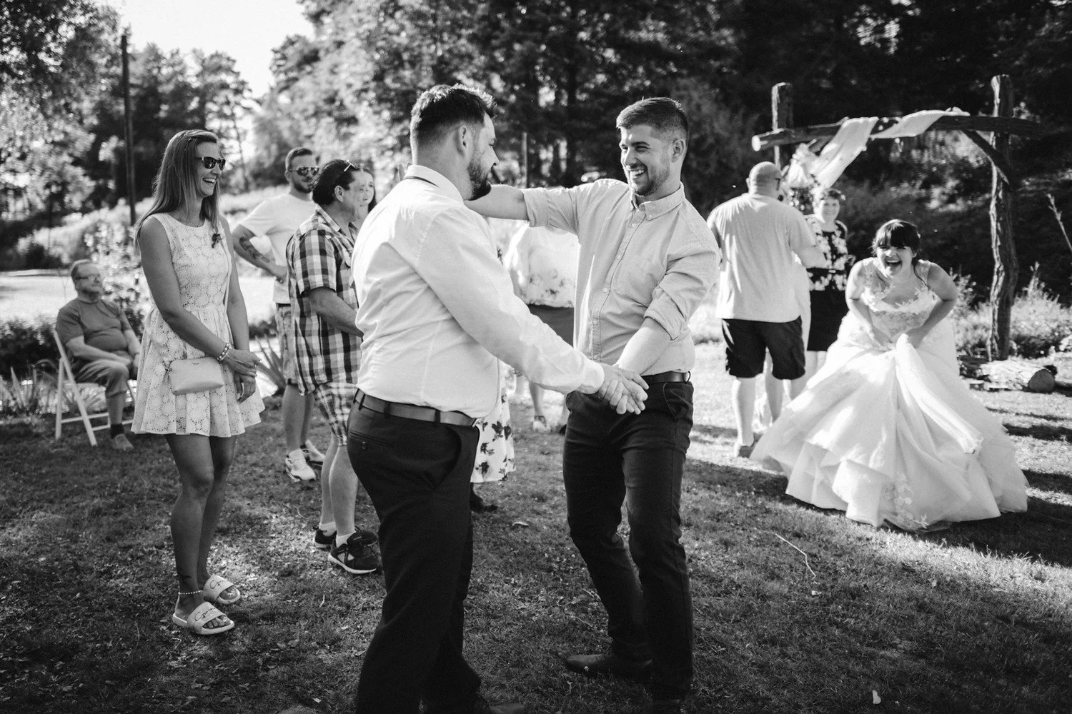 Pavel si při venkovním tanci podává ruku s mužem, zatímco Radka tančí v pozadí.