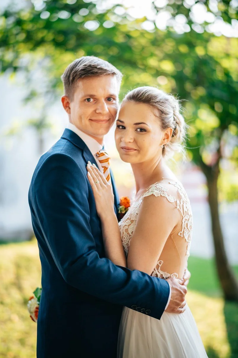 Alex a Fanda stojí v objetí před rozostřenou zelení.