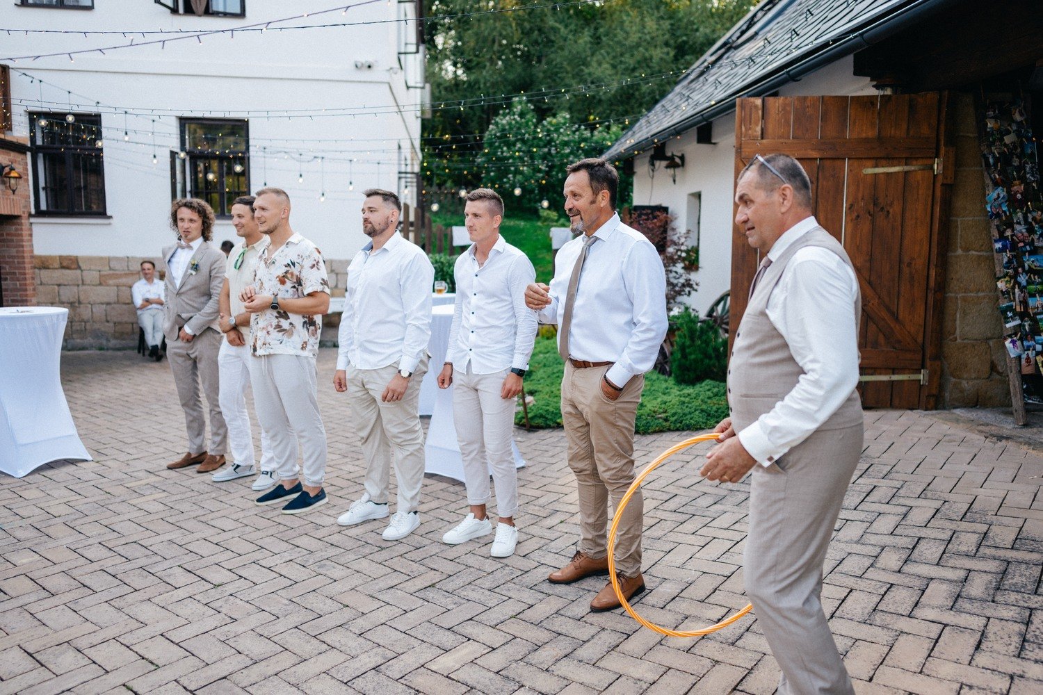 Řada mužů čeká na svatební hru, zatímco jeden drží velký kruh