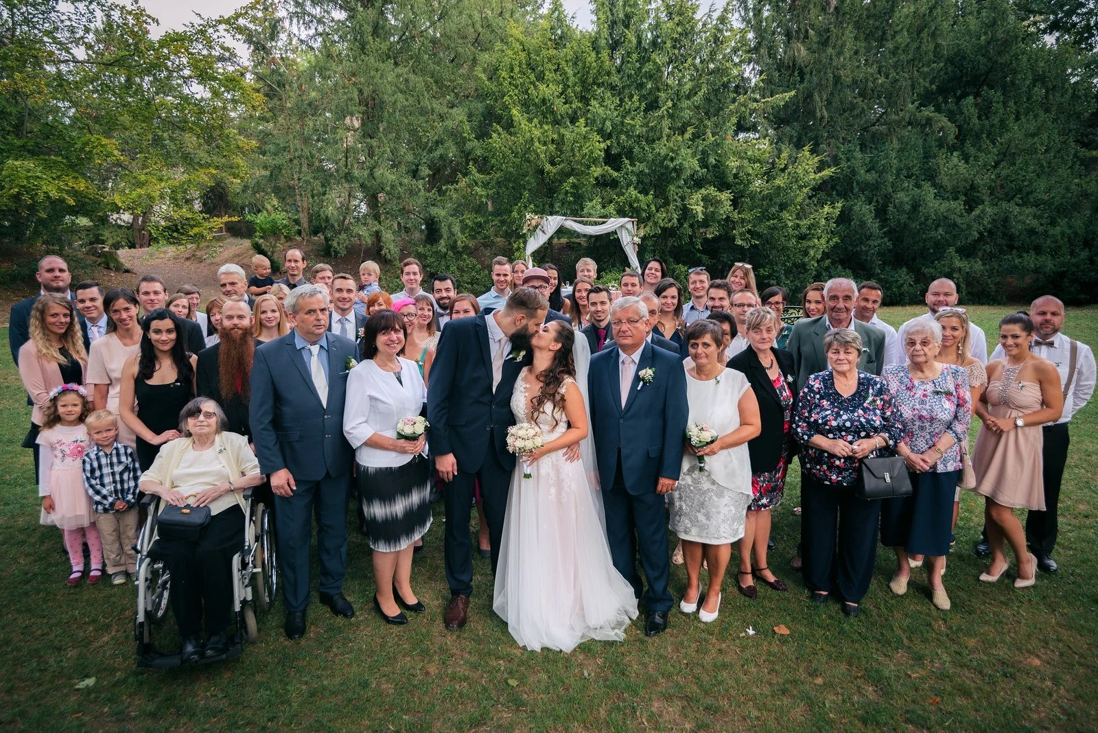 Velká skupina lidí stojí pohromadě v širokém portrétu na trávníku.