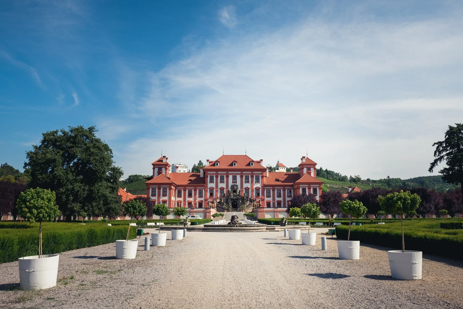 Symetrický široký pohled na historickou budovu a zahradní osu zakládá nové prostředí.