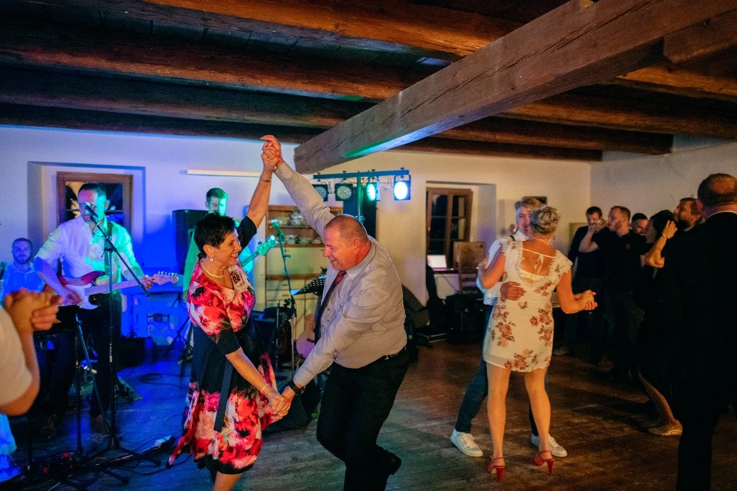 Muž a žena tančí se spojenýma rukama před živou kapelou.
