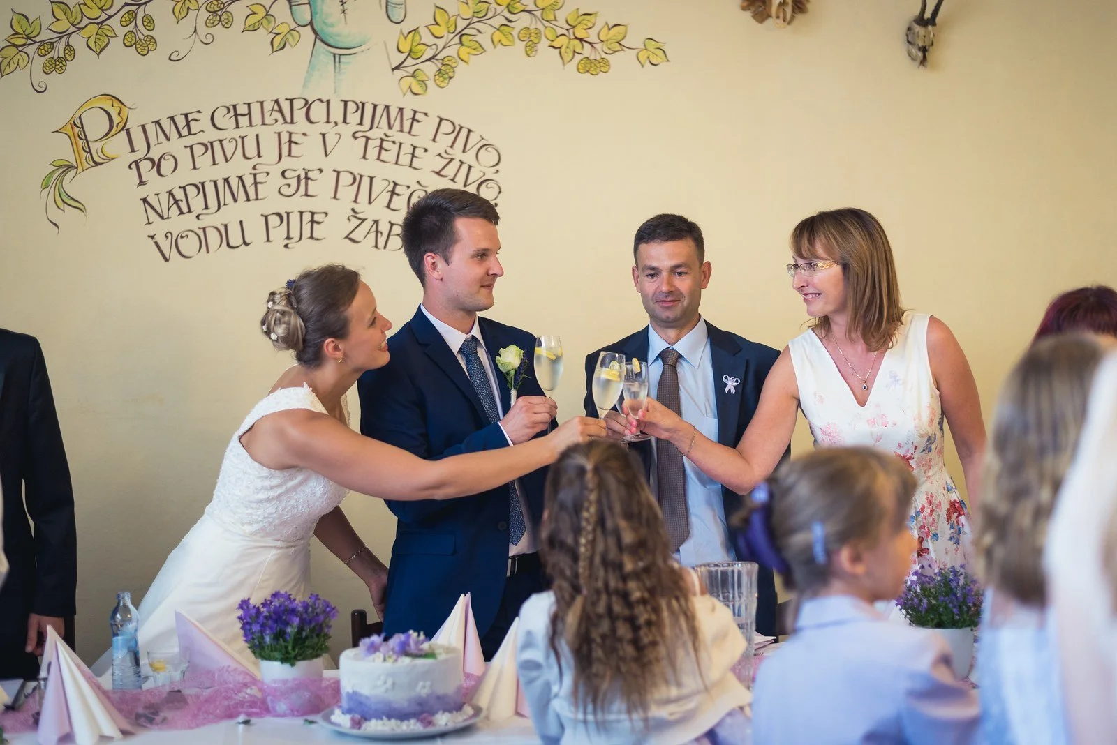 Žena pronáší přípitek před novomanželi a hosty.