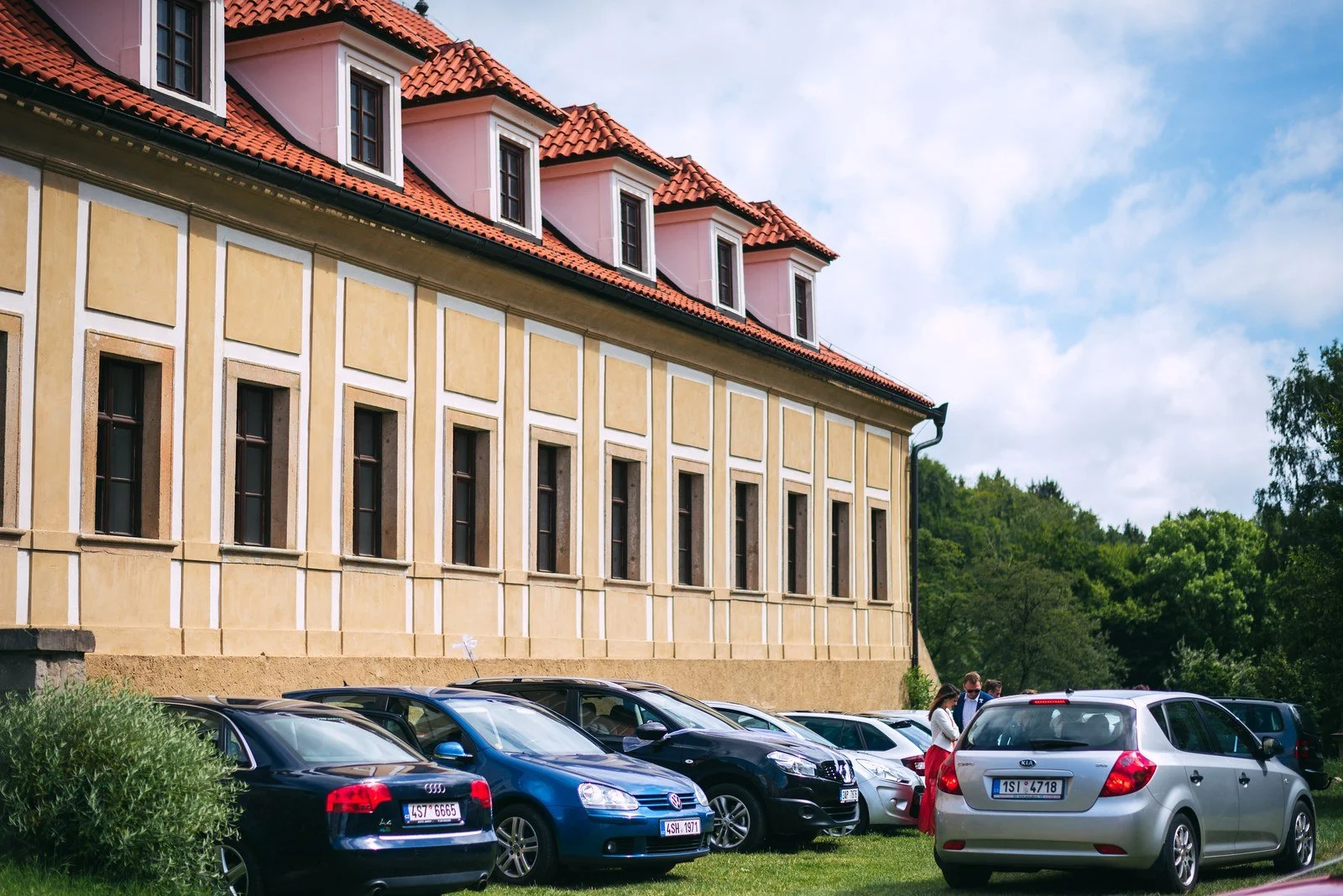 Detail rukou upravujících prameny hnědých vlasů u tváře sedící ženy.