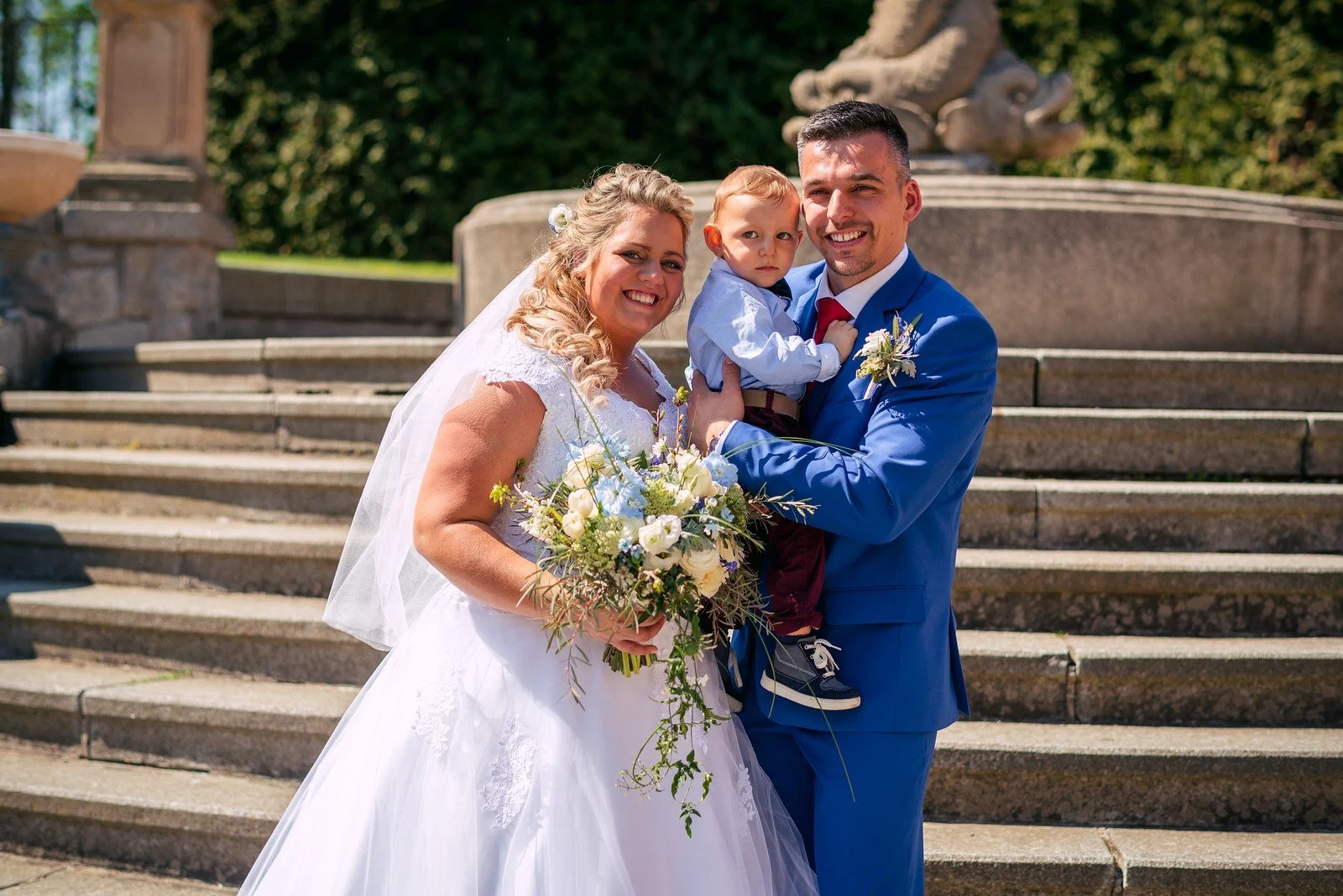 Novomanželé a dítě při společné fotografii po obřadu.