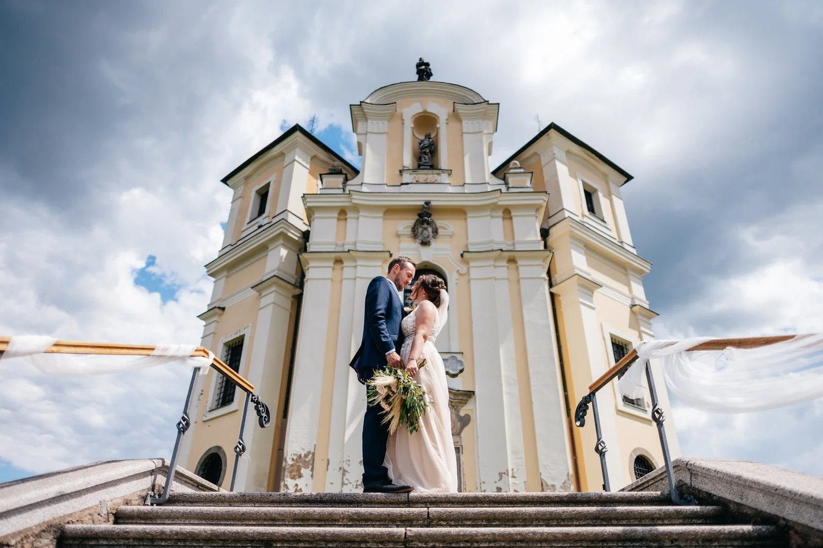 Nízký pohled na dvojici před kostelem zdůrazňuje architekturu.