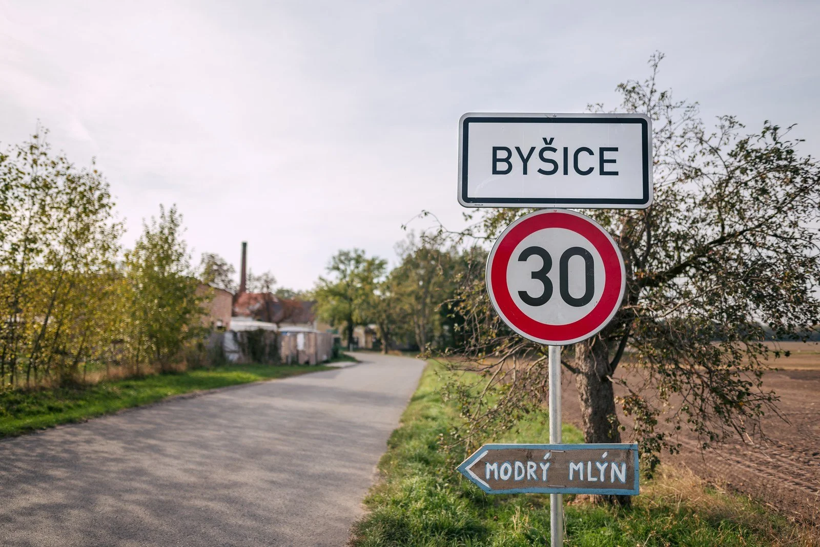 Silnice u cedule obce Býšice a dopravní značky s omezením rychlosti na 30 km/h.