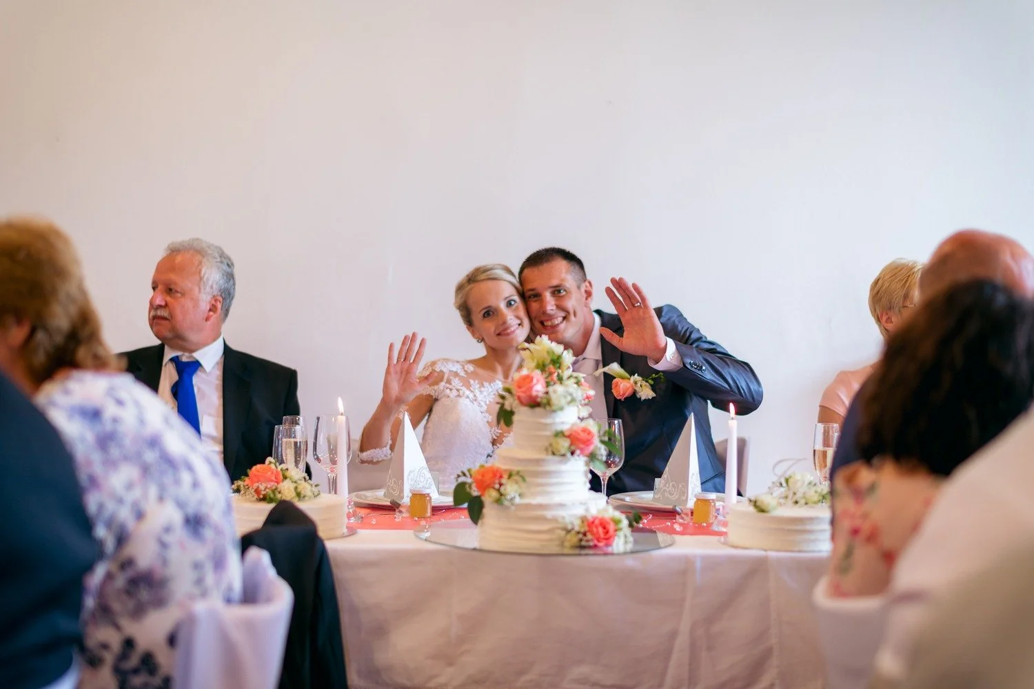 Jitka a Lukáš mávají od čela stolu za trojicí květinově zdobených dortů.