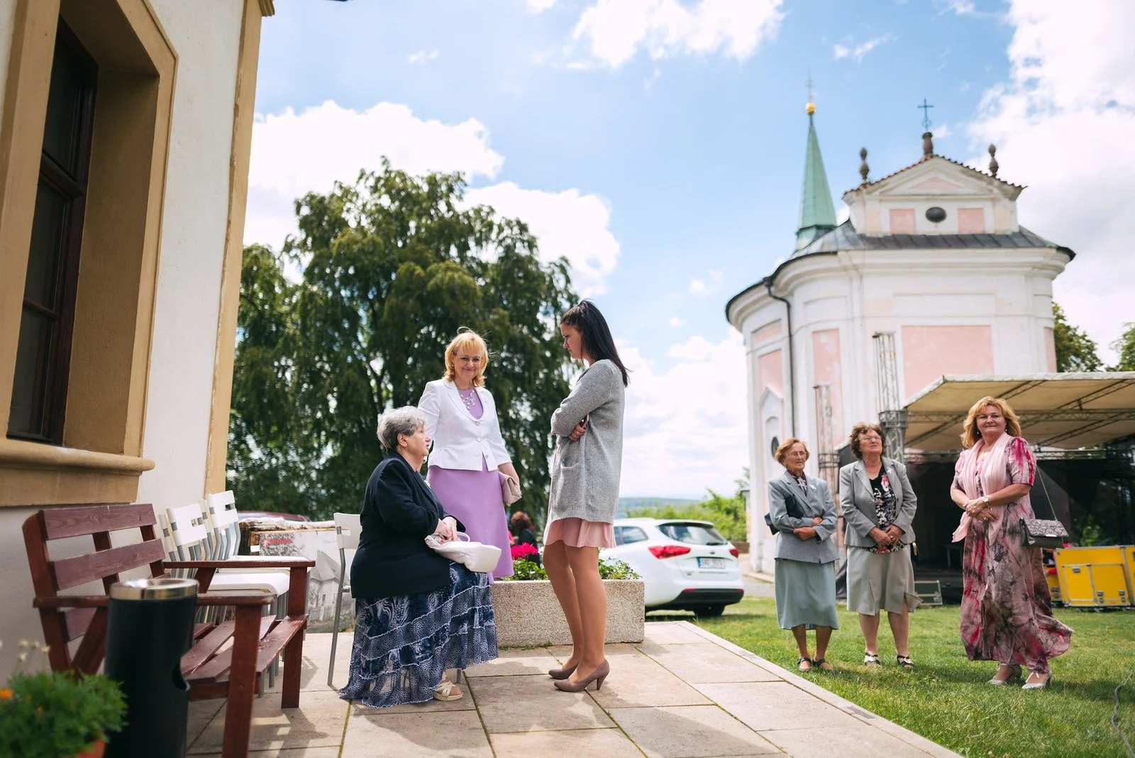Detail ženy se skloněnou hlavou, zatímco jí druhá osoba upravuje vlasy u spánku.