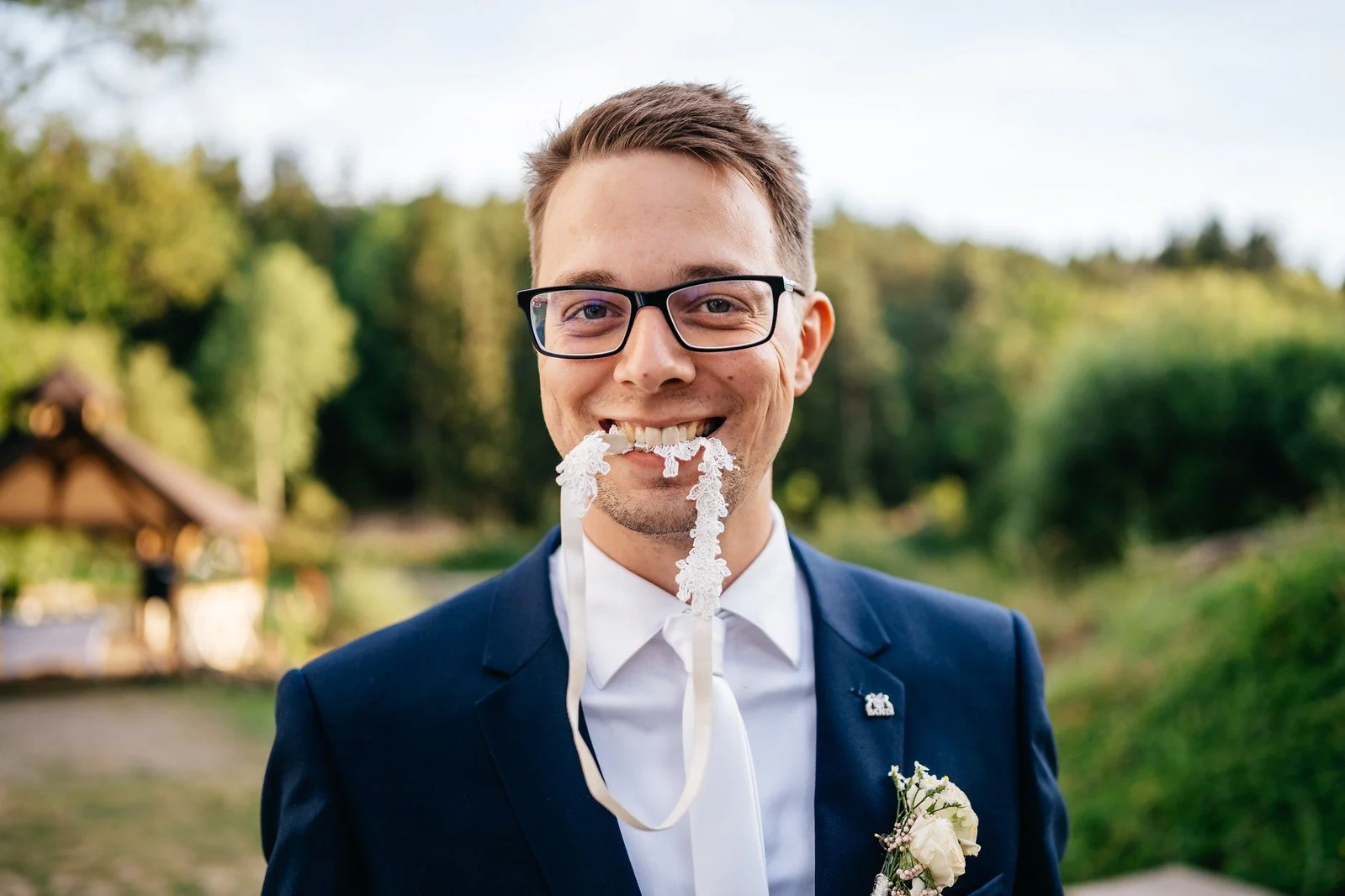 Ženich s brýlemi se usmívá s kouskem krému na nose a vidličkou u úst.