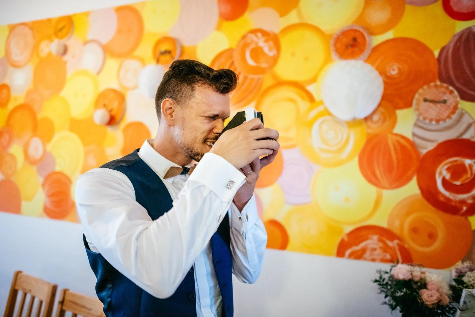 Muž pózuje s kulatou fotokoutkovou rekvizitou před barevným pozadím.