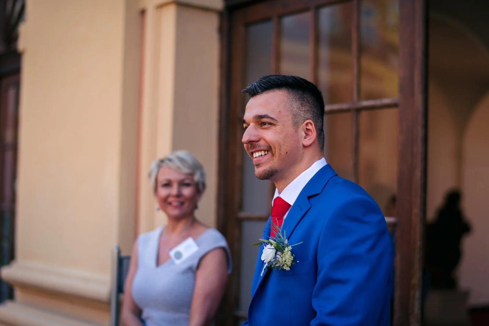 Dvě osoby u okna v interiéru Zámku Dobříš před obřadem.