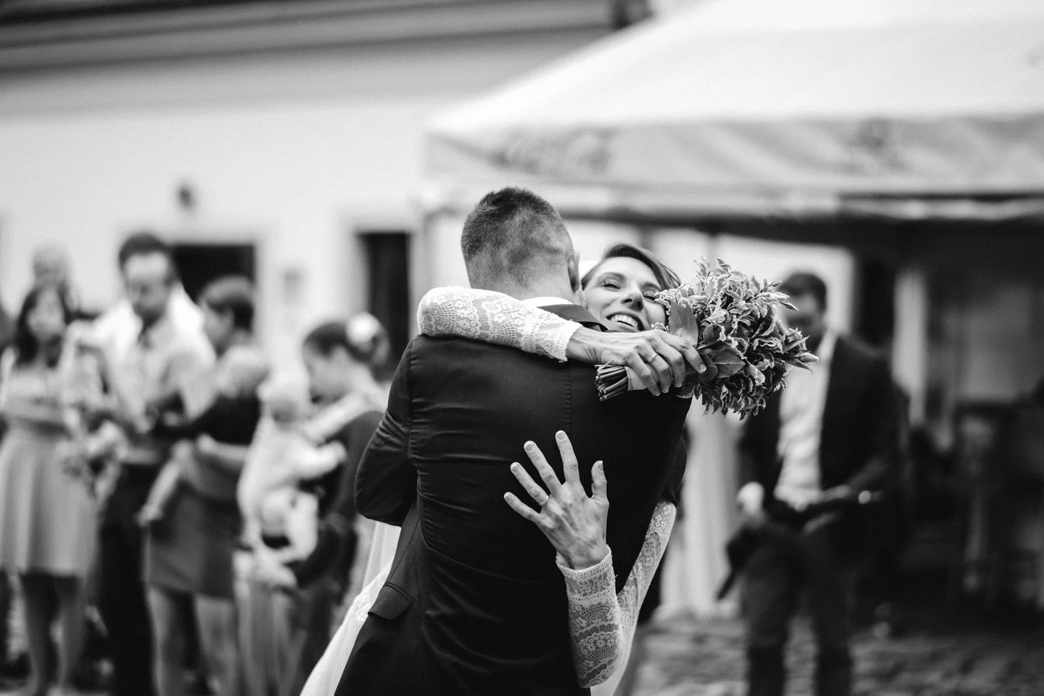 Černobílý záběr pevného objetí během gratulací po obřadu.