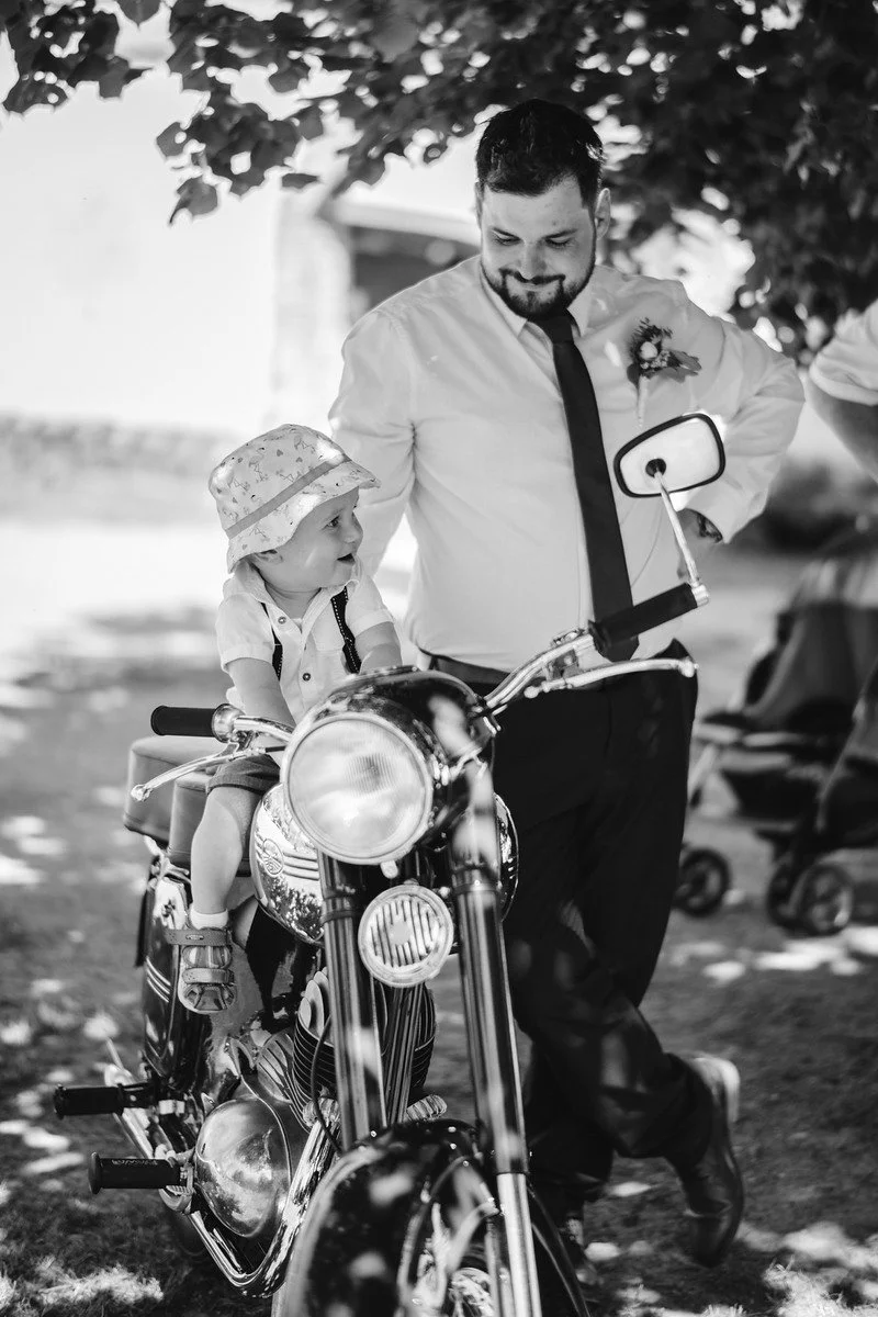 Černobílý snímek zachycuje Pavla u řídítek historického motocyklu.