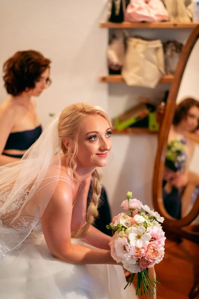 Nevěsta s kyticí sedí při posledních úpravách vlasů
