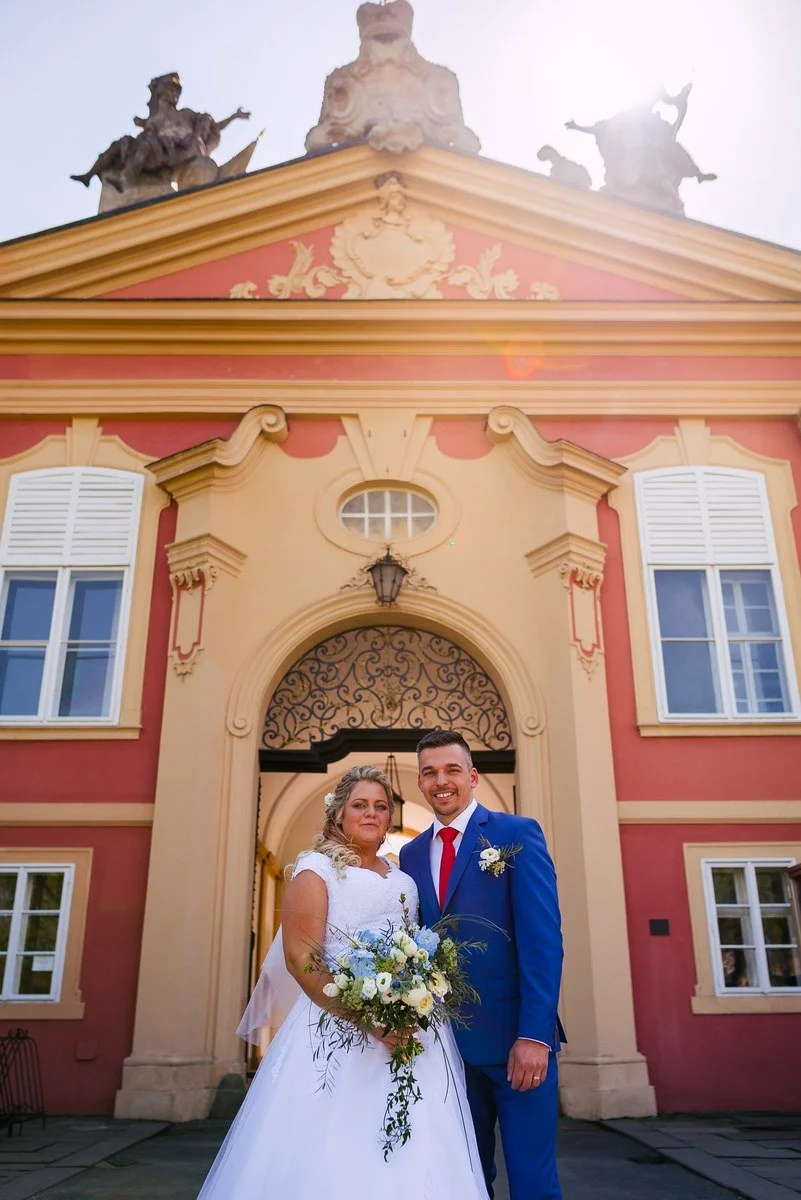 Pár stojí pod obloukem historické architektury.
