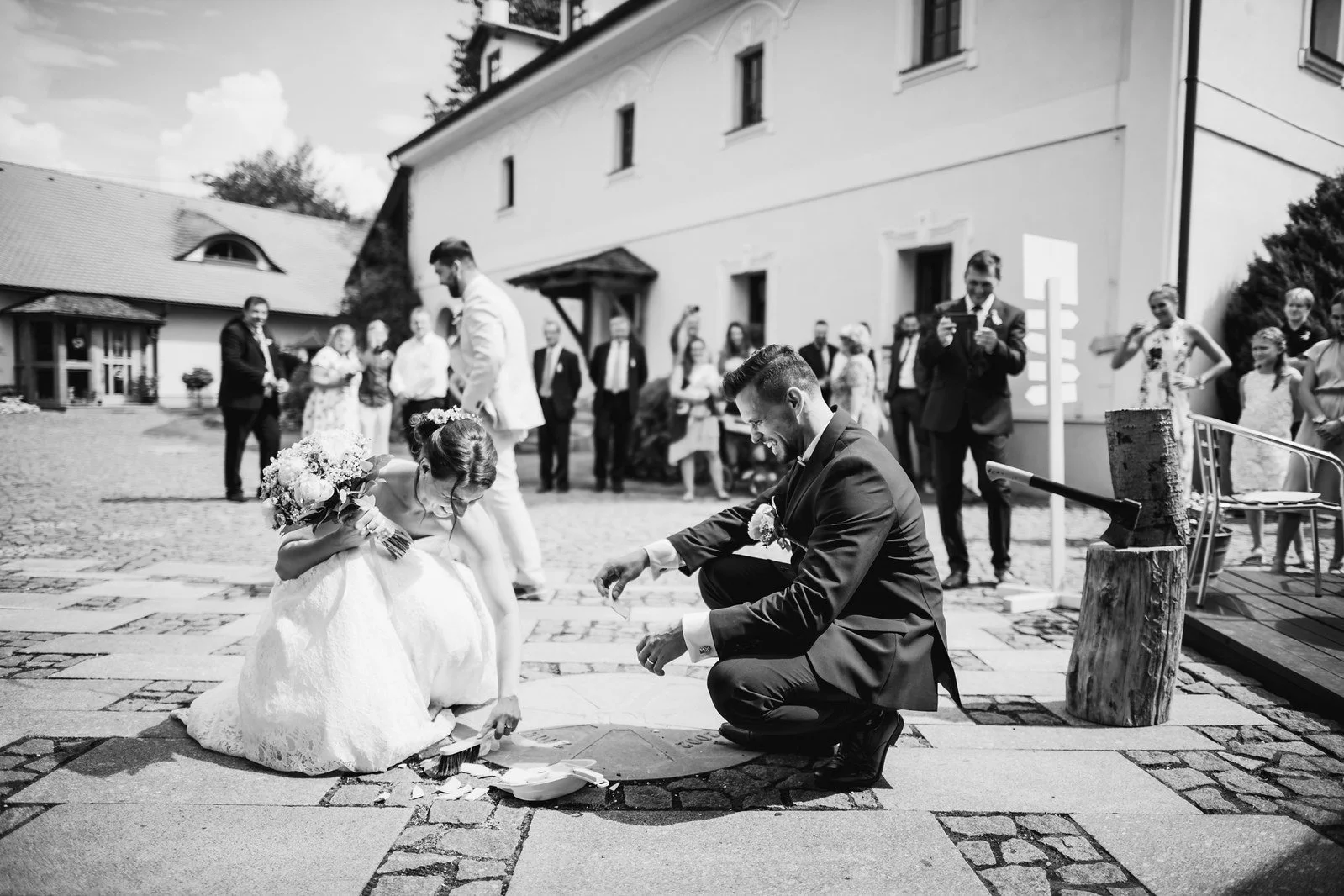 Černobílý moment s fotografem klečícím ve dvoře během programu.