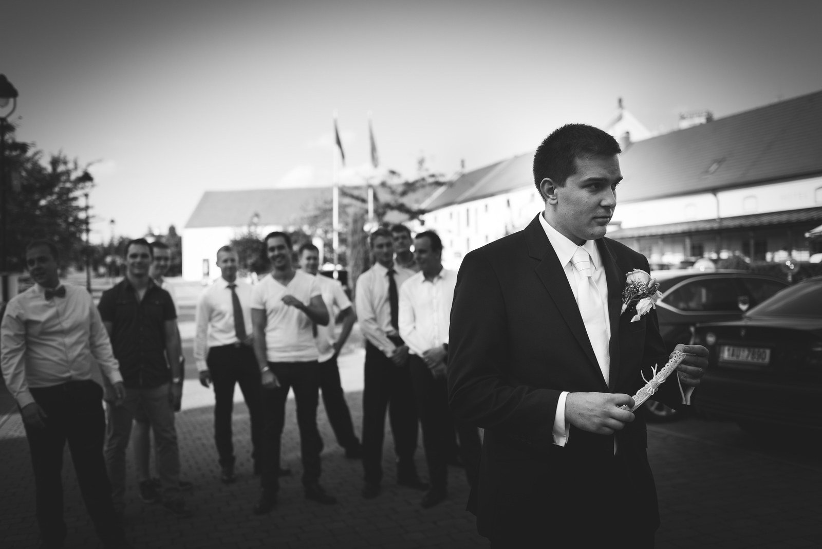 Černobílý venkovní portrét muže v obleku před řadou přihlížejících izoluje krátkou akční pauzu.