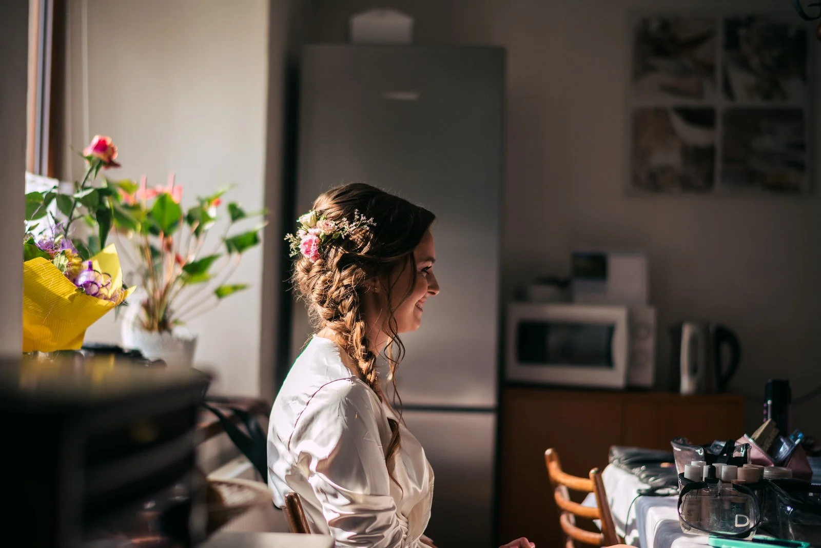 Sedící žena v županu se připravuje u stolu v kuchyni.