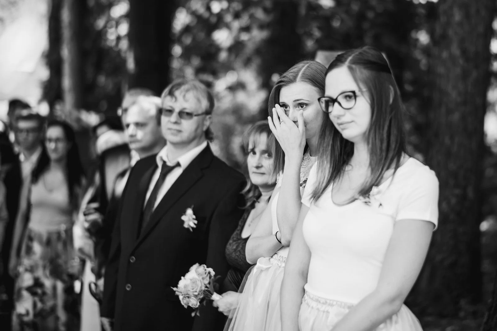 Hosté sledují lesní obřad v řadě vedle sebe.
