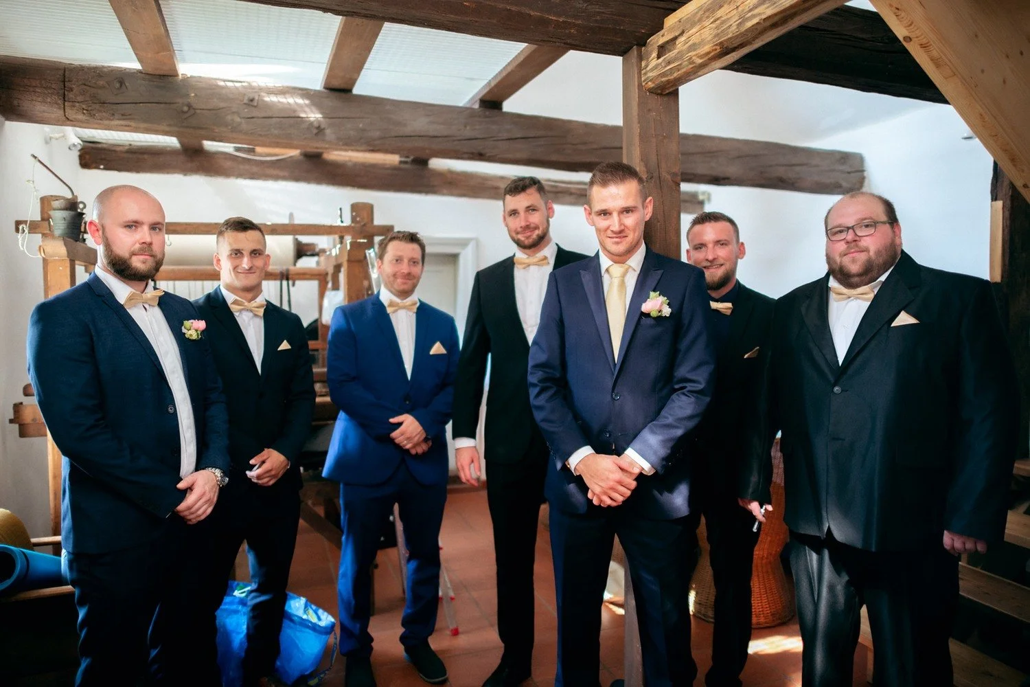 Skupina mužů v oblecích před dřevěnými trámy