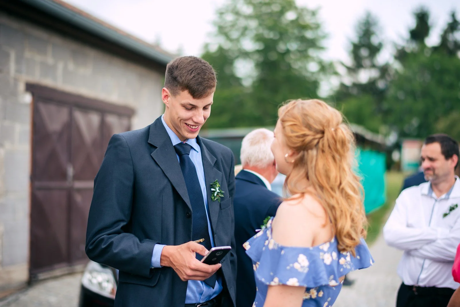 Žena venku připíná květinu muži v modrém obleku.