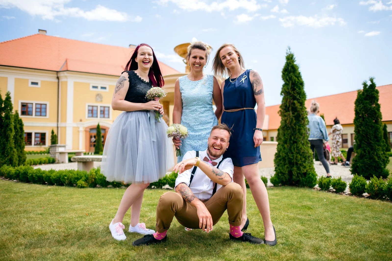 Klára a Lukáš pózují venku uprostřed početné skupiny svatebních hostů.