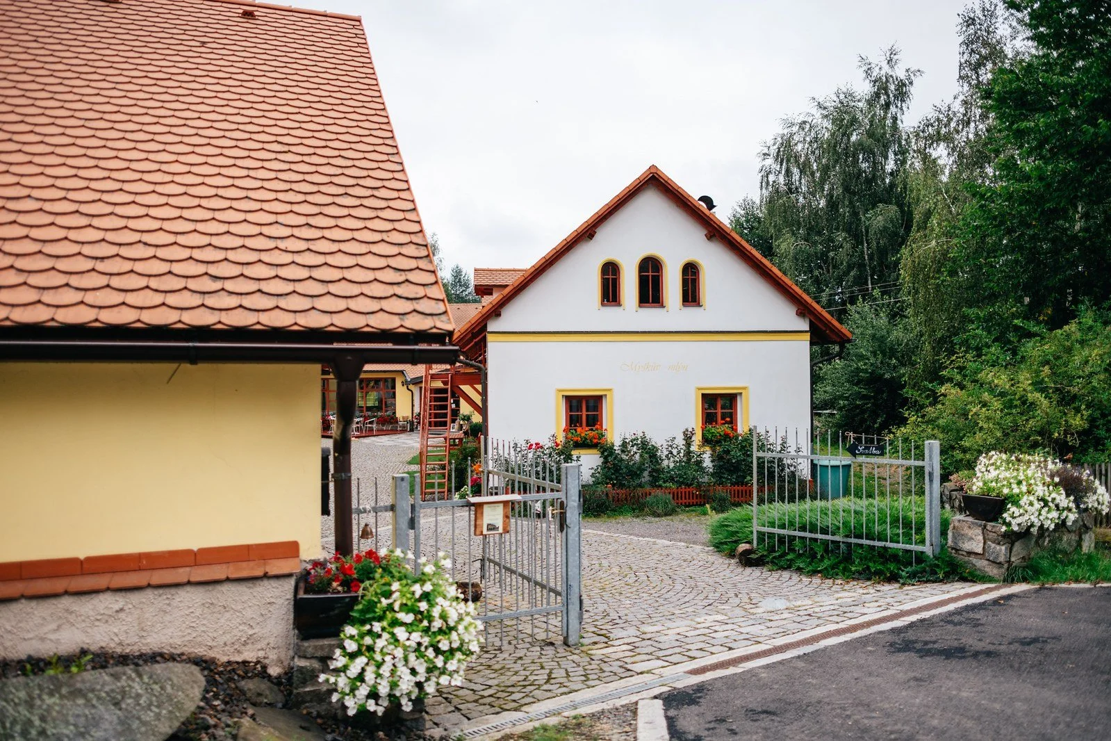 Široký pohled na areál mlýna a okolní zeleň na začátku dne.