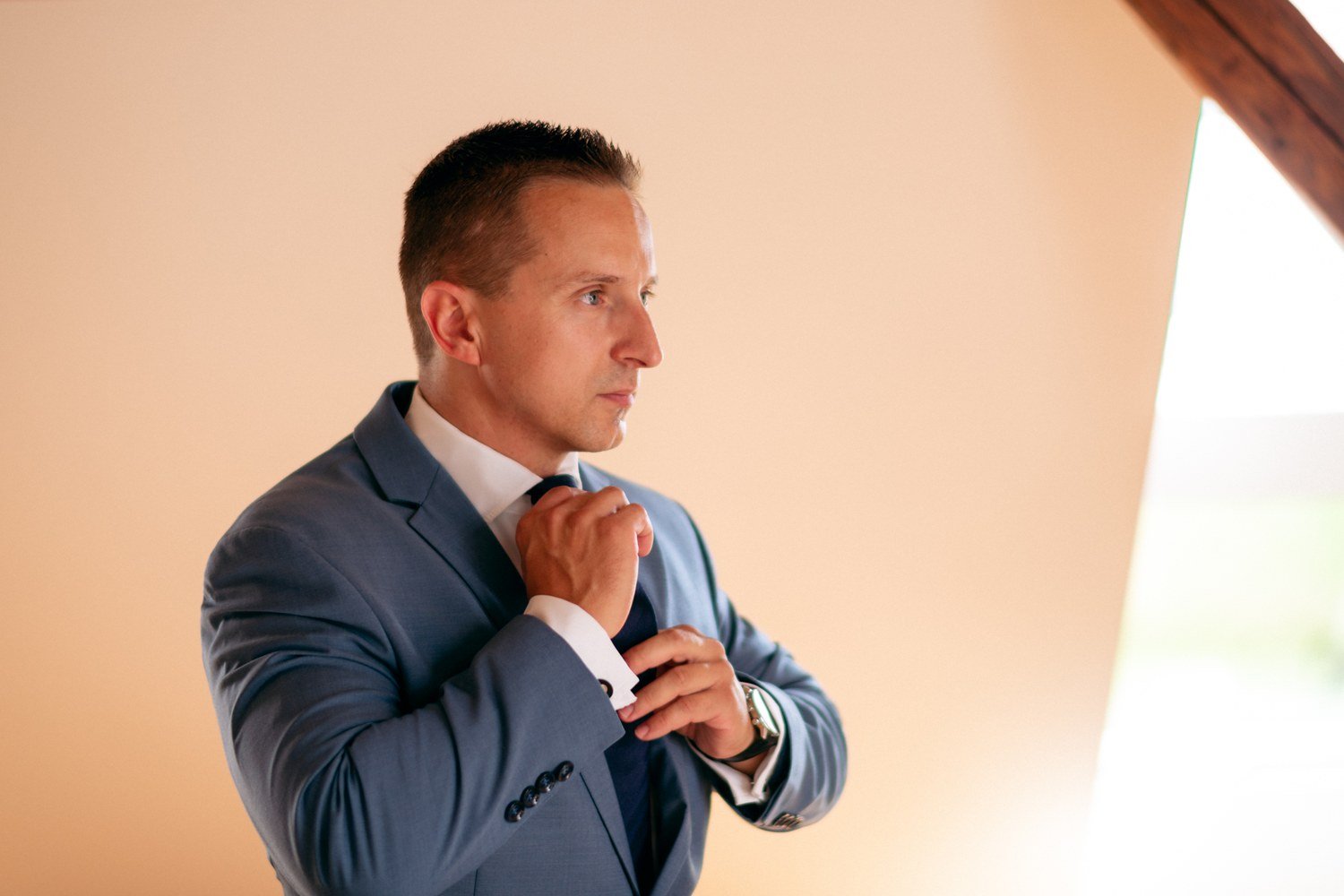 Souředěné vázání kravaty, teplé světlo a čistý portrétní rám dávají ženichovi samostatný moment.
