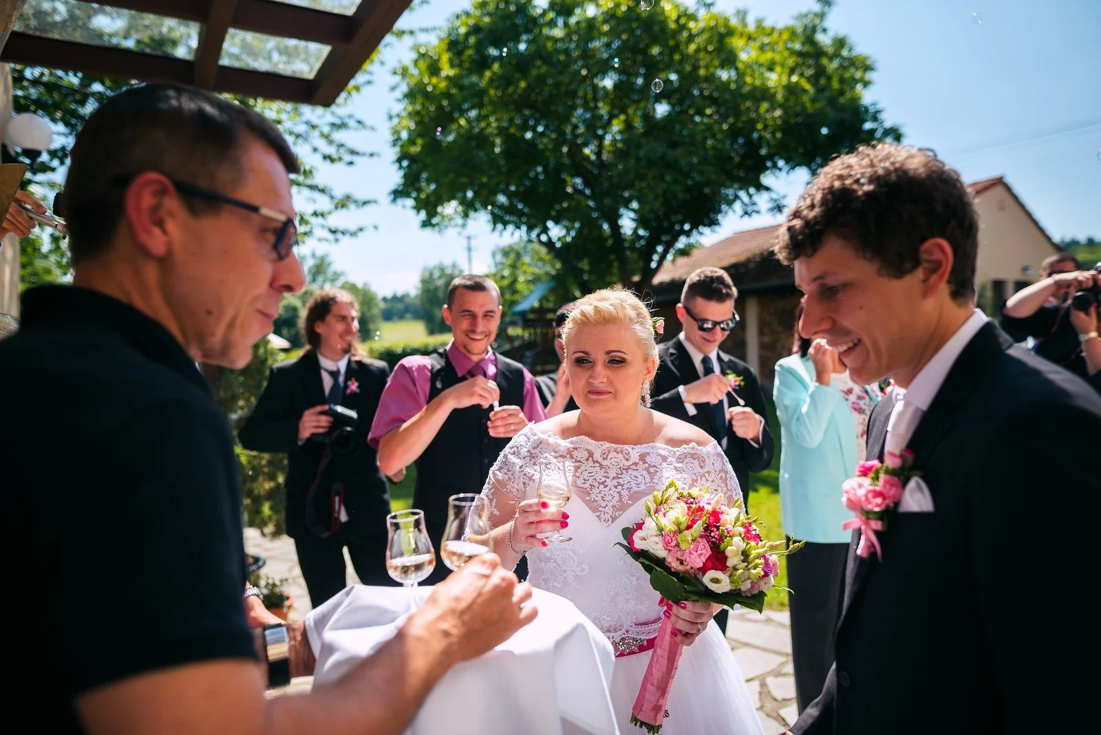 Sklenky se setkávají při venkovním přípitku uprostřed kruhu lidí.