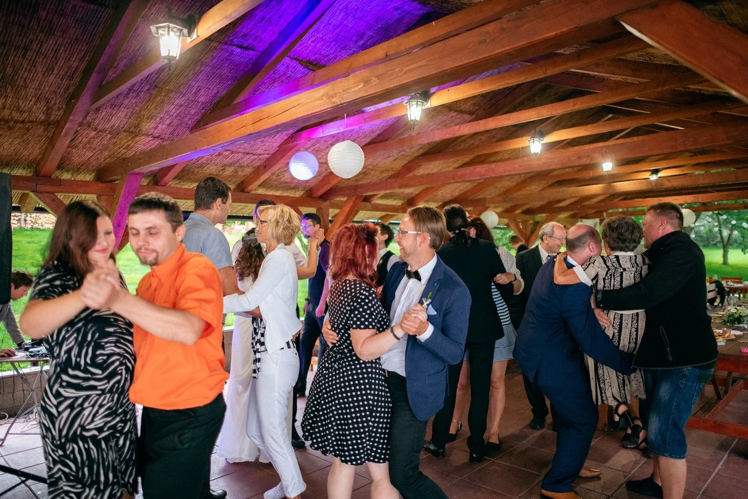 Hosté tančí společně pod barevnými světly v pavilonu.