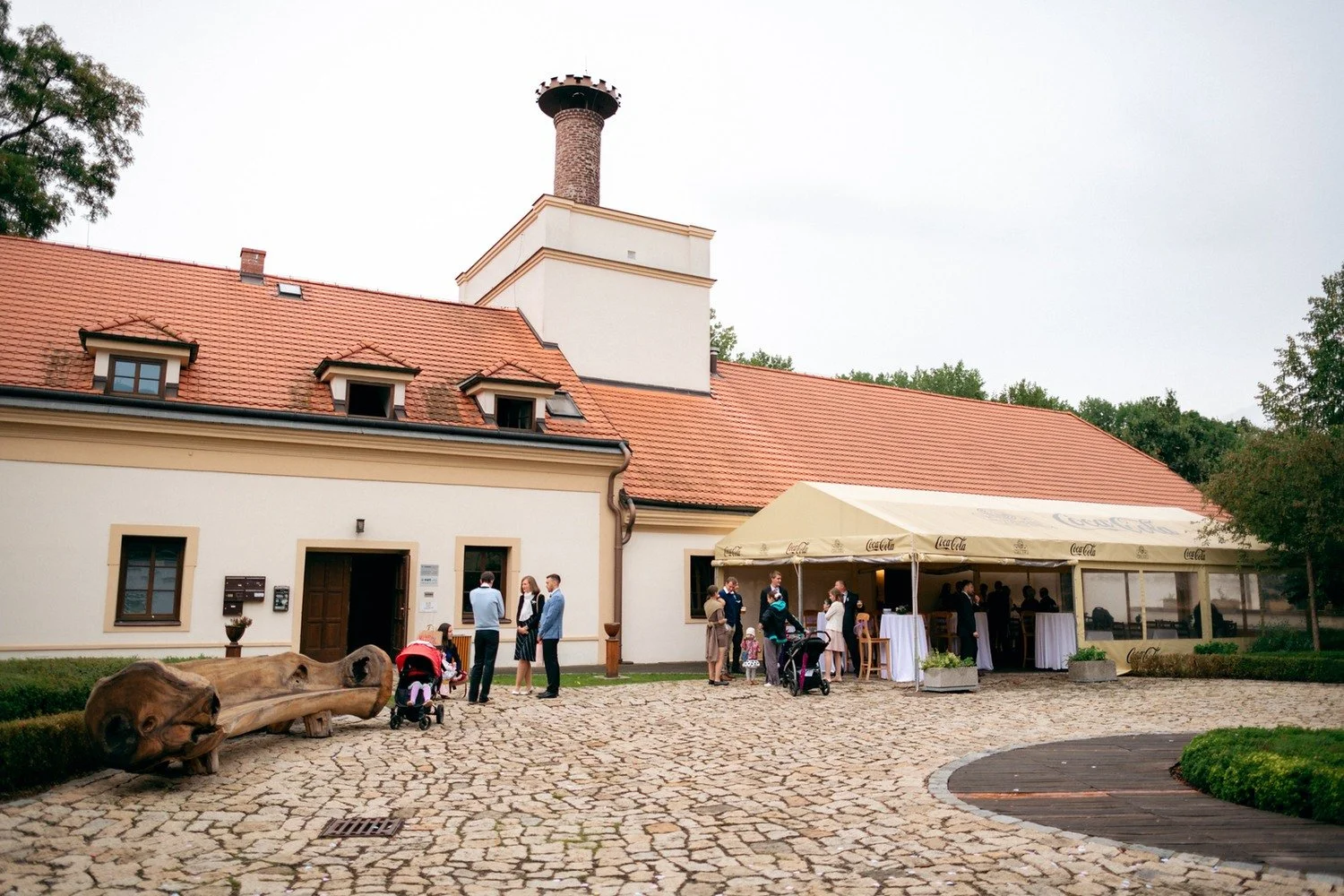 Hosté se scházejí na dlážděném dvoře historické budovy.