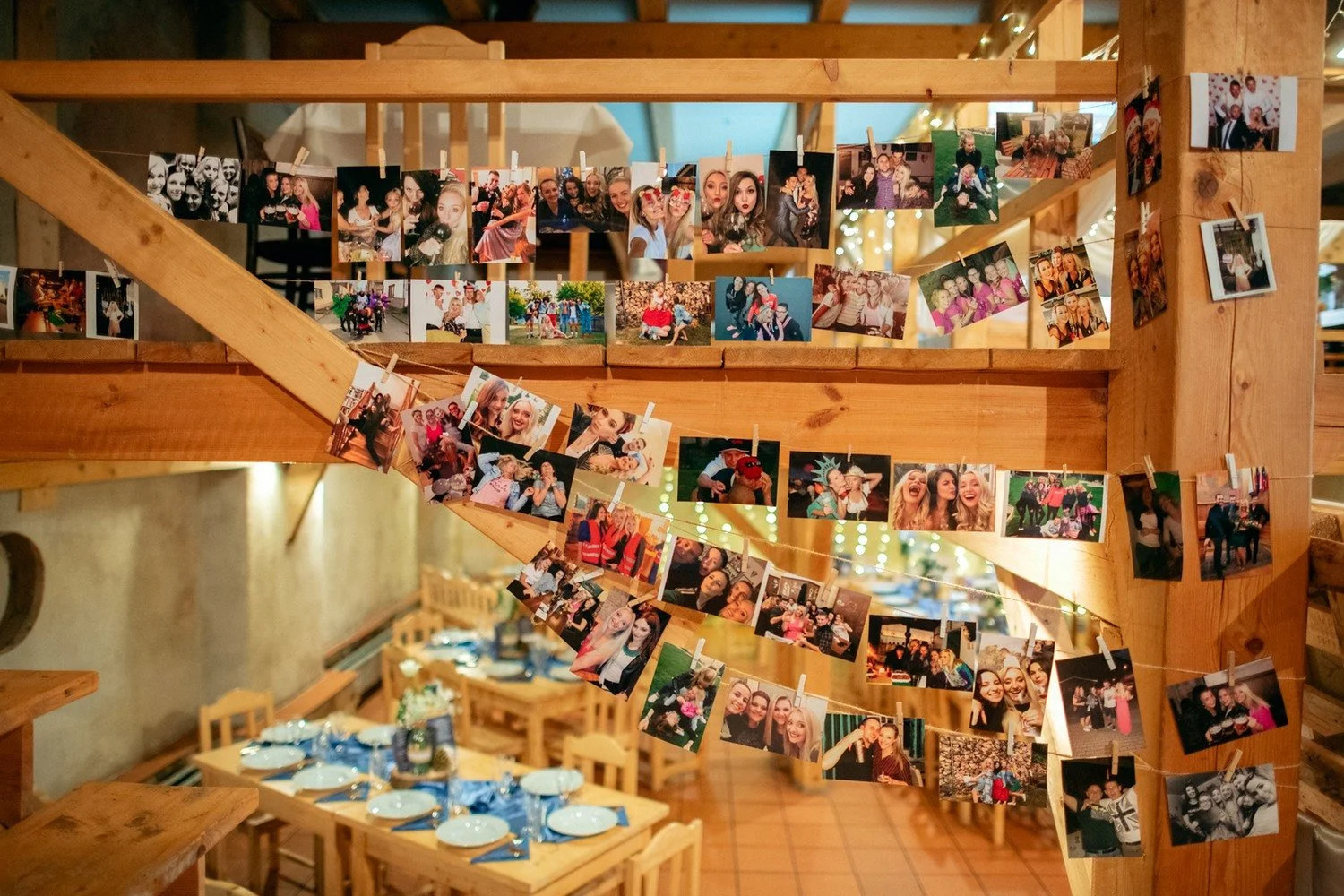 Stěna plná vytištěných fotografií nad svatební tabulí