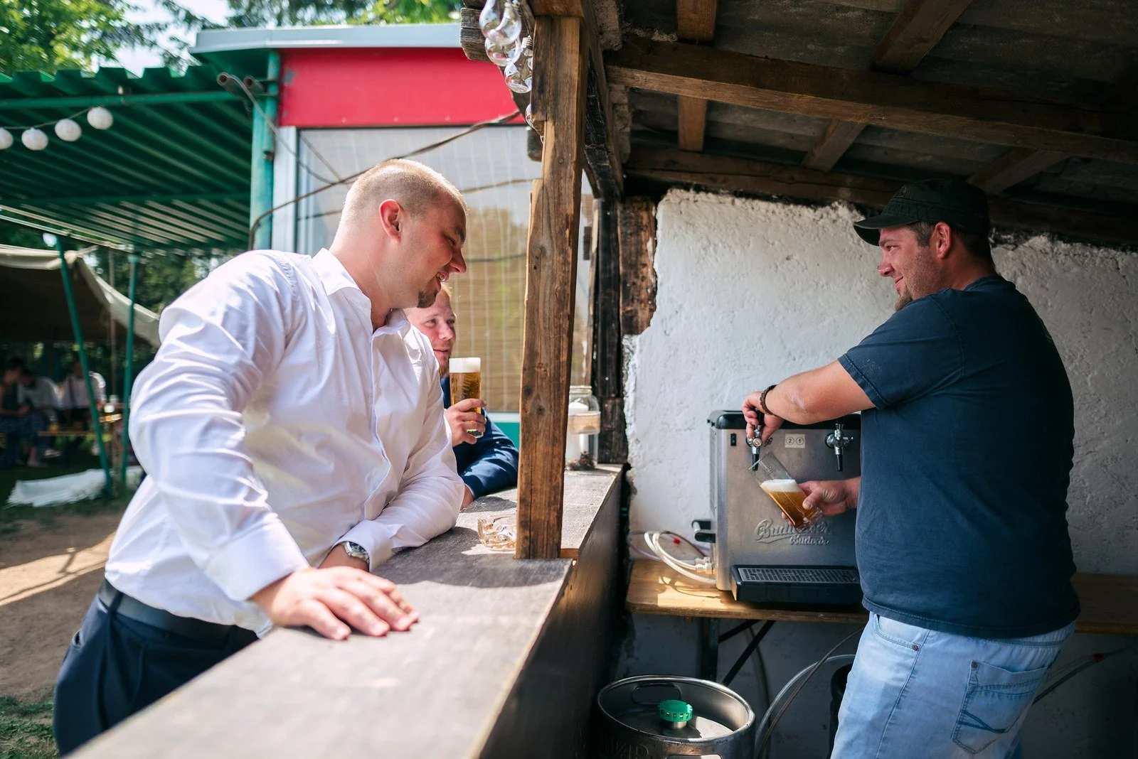 Dva muži připravují jídlo u otevřeného venkovního zařízení.