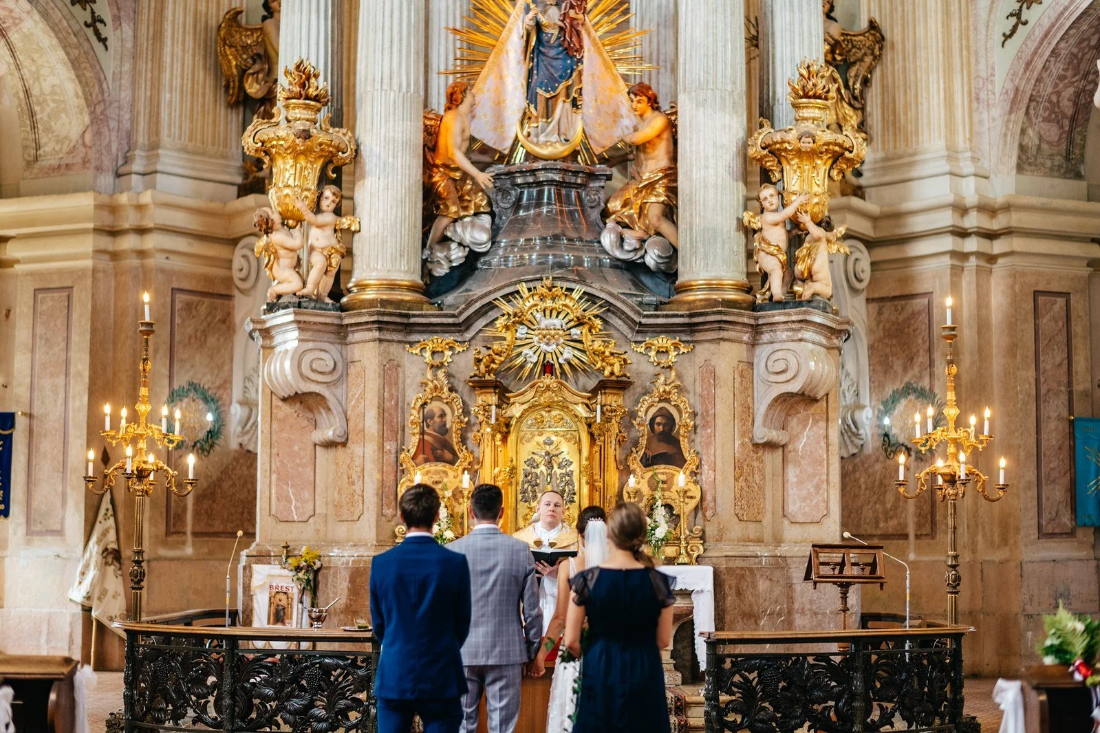 Široký pohled na dvojici stojící před oltářem.