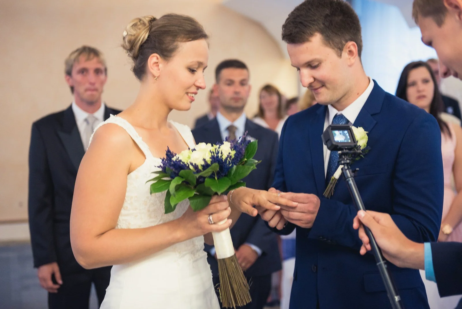 Nevěsta nasazuje ženichovi prsten během obřadu.